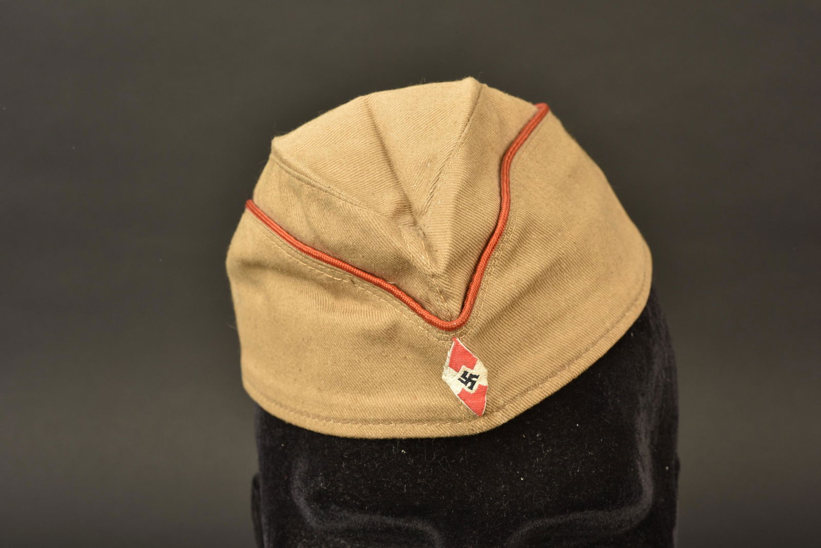 Calot HJ. Hitlerjugend cap: Calot Hitlerjugend. En toile cachou. Lisere rouge faisant le tour de la coiffe. Insigne HJ tisse monte main. Interieur double en satinette grise. Taille 53. Bandeau de transpiration en faux cuir marro