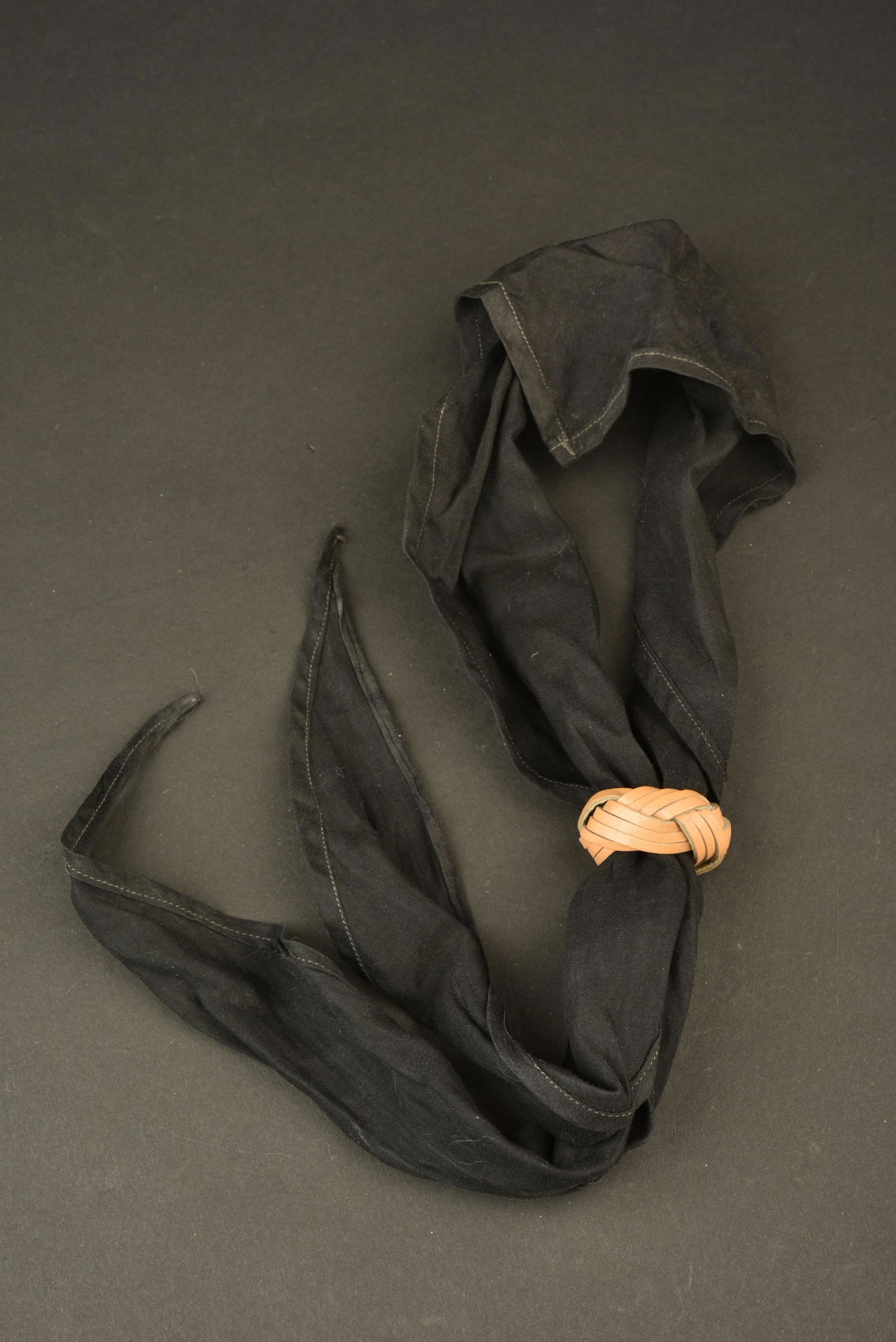 Foulard HJ. Hitlerjugend scarf: Foulard Hitlerjugend. Foulard en tissu coton noir. Sans marquages visibles. NÅ“ud realise en lanieres de cuir. Probablement un nÅ“ud scout ou civil. A noter une certaine usure et patine de la pi