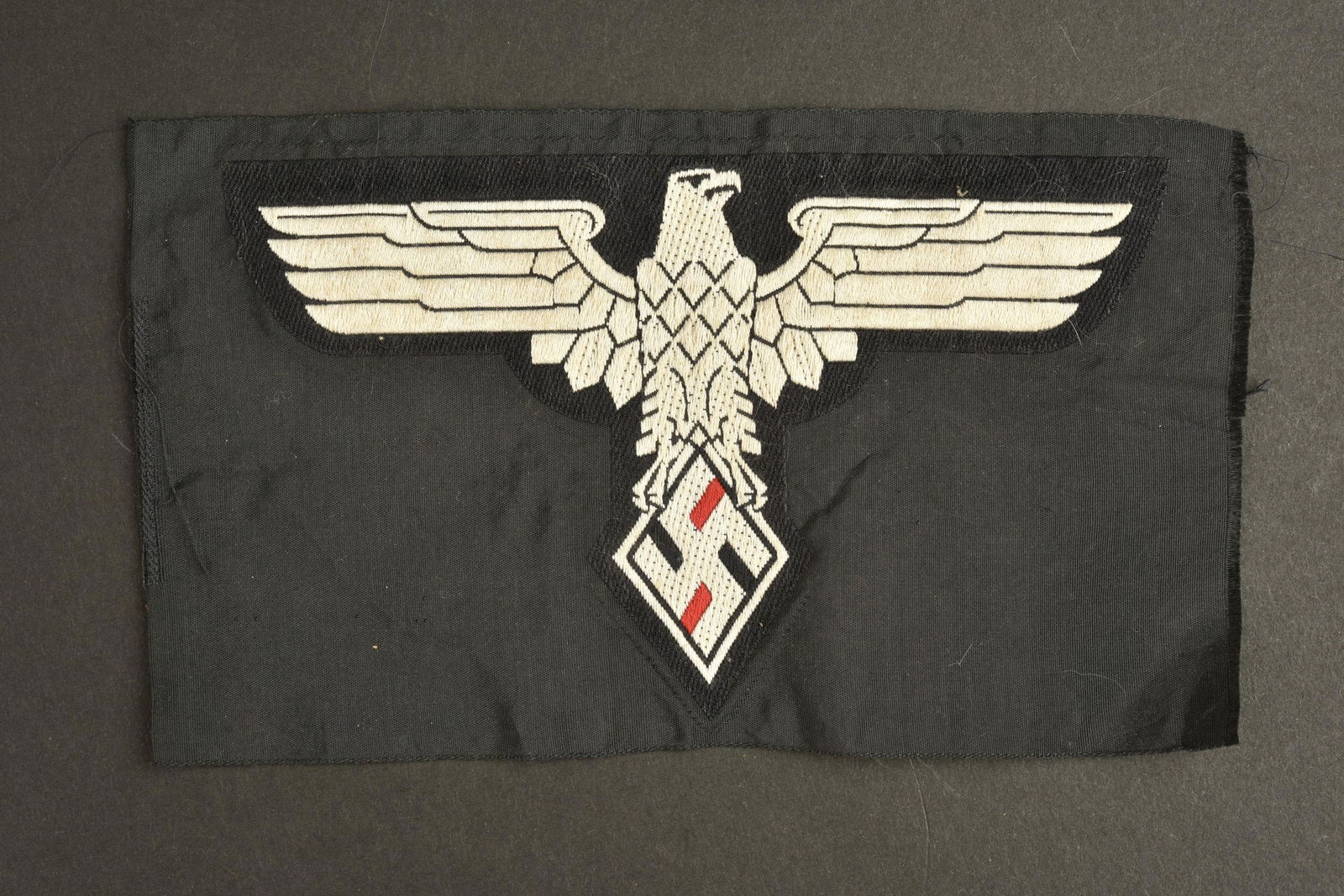 Insigne NSD. NSD insignia: Insigne NSD. Modele Bevo sur fond noir. Sans marquages visibles. Dimensions 10 x 17 cm. A noter une certaine usure et patine de la piece. Etat II+. NSD badge. Bevo model on black background. Without v