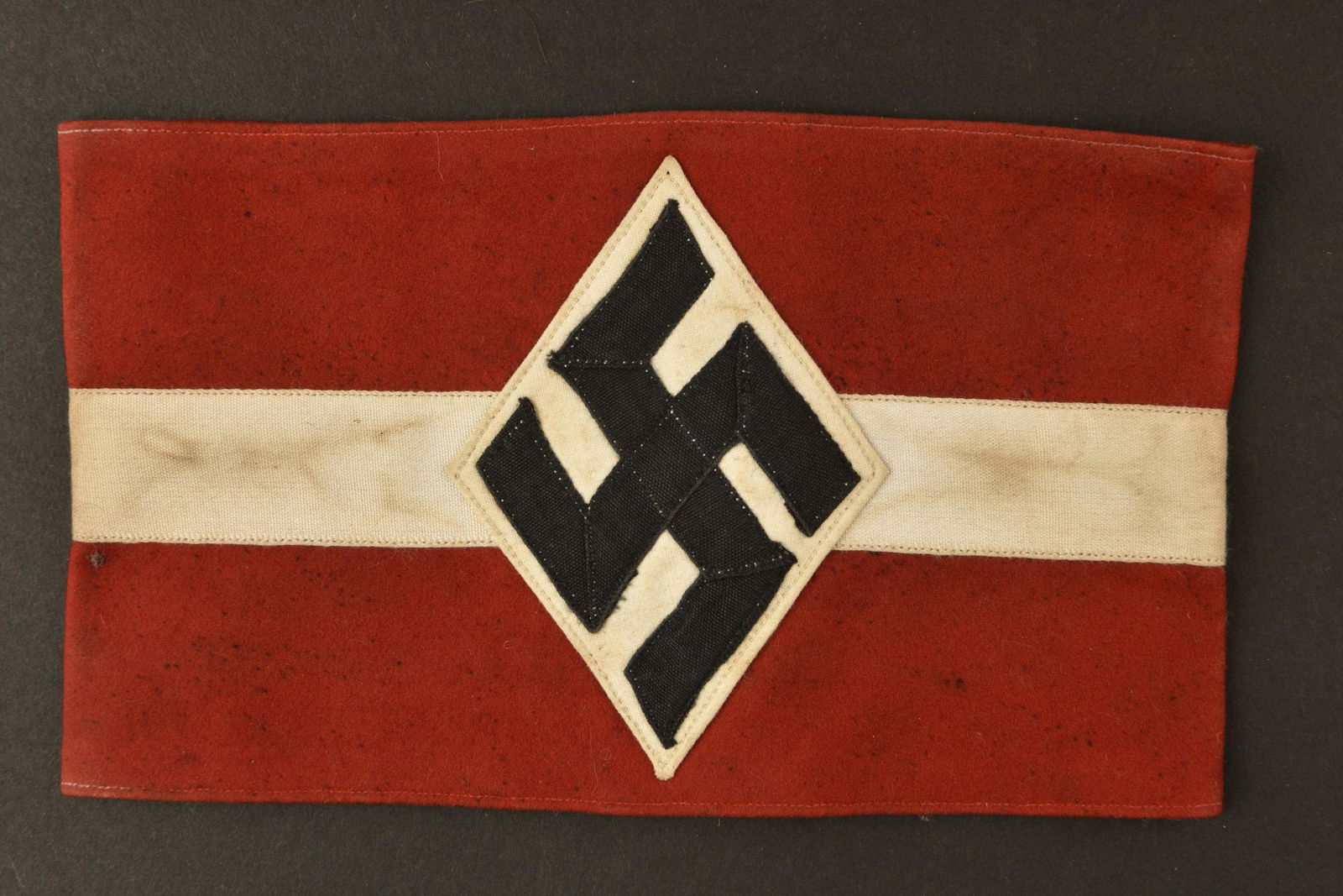 Brassard NSD. NSD Armband: Brassard NSD. En laine, insigne tisse et rapporte. Sans marquages visibles. A noter une certaine usure et patine de la piece, ainsi quelques taches et trous de mite. Etat II+. NSD armband. In wool, wo