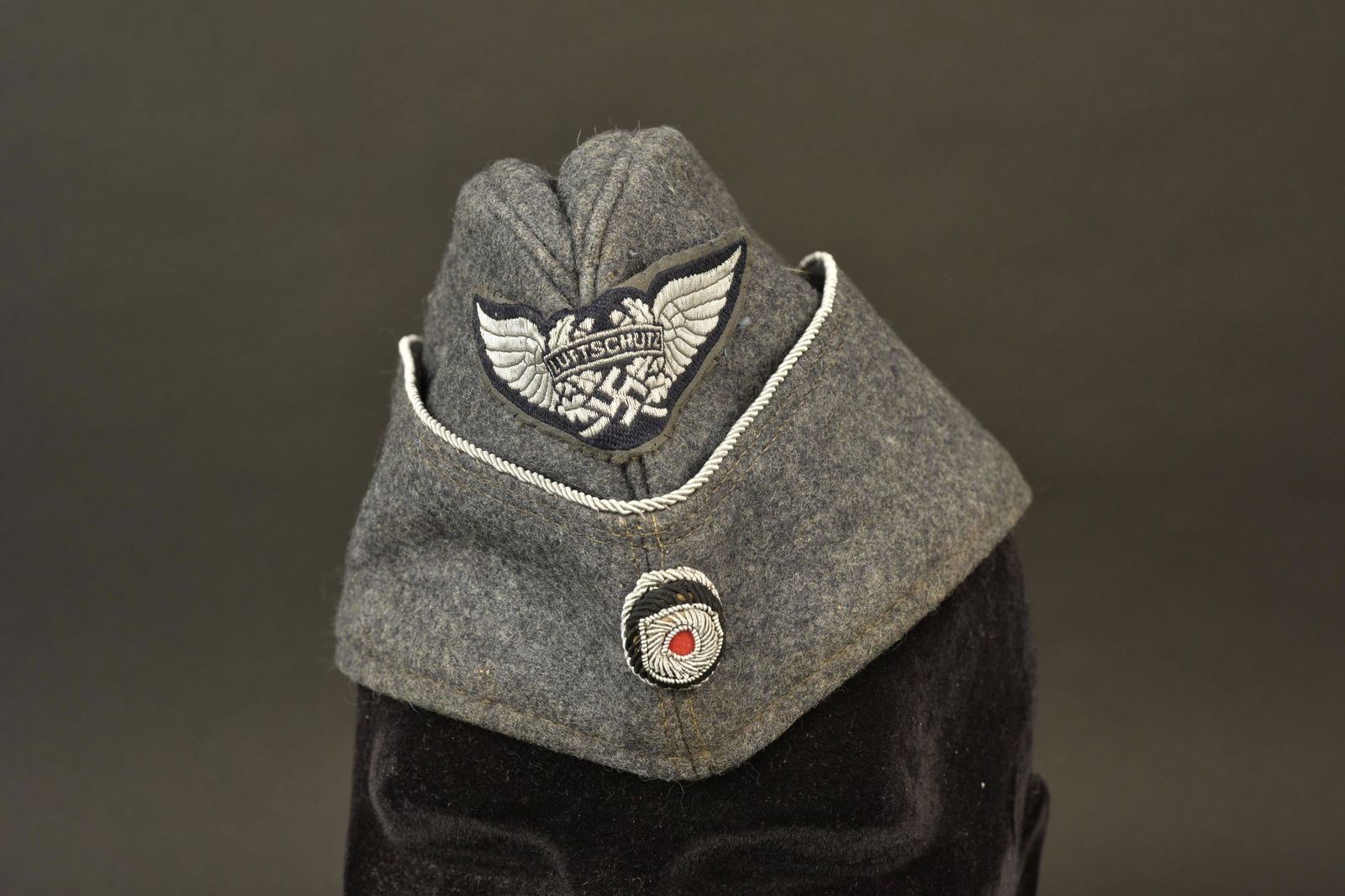 Calot officier Luftschutz. Luftschutz cap: Calot d'officier Luftschutz. En drap gris/bleu. Galon argent faisant le tour de la coiffure. Insigne Luftschutz Bevo monte main et partiellement decousu. Cocarde en cannetille argent montee main. Inte