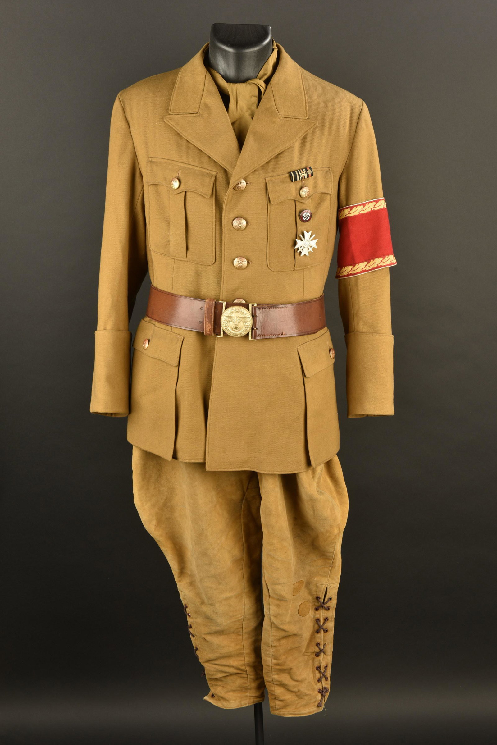 Uniforme de Politischer Leiter. Politischer Leiter Uniform: Uniforme de Politischer Leiter. Comprenant un pantalon culotte de cheval en velours kaki, la majorite des boutons sont presents. Bas des jambes fermant par un lacage. Nombreuses reparations sur les ja