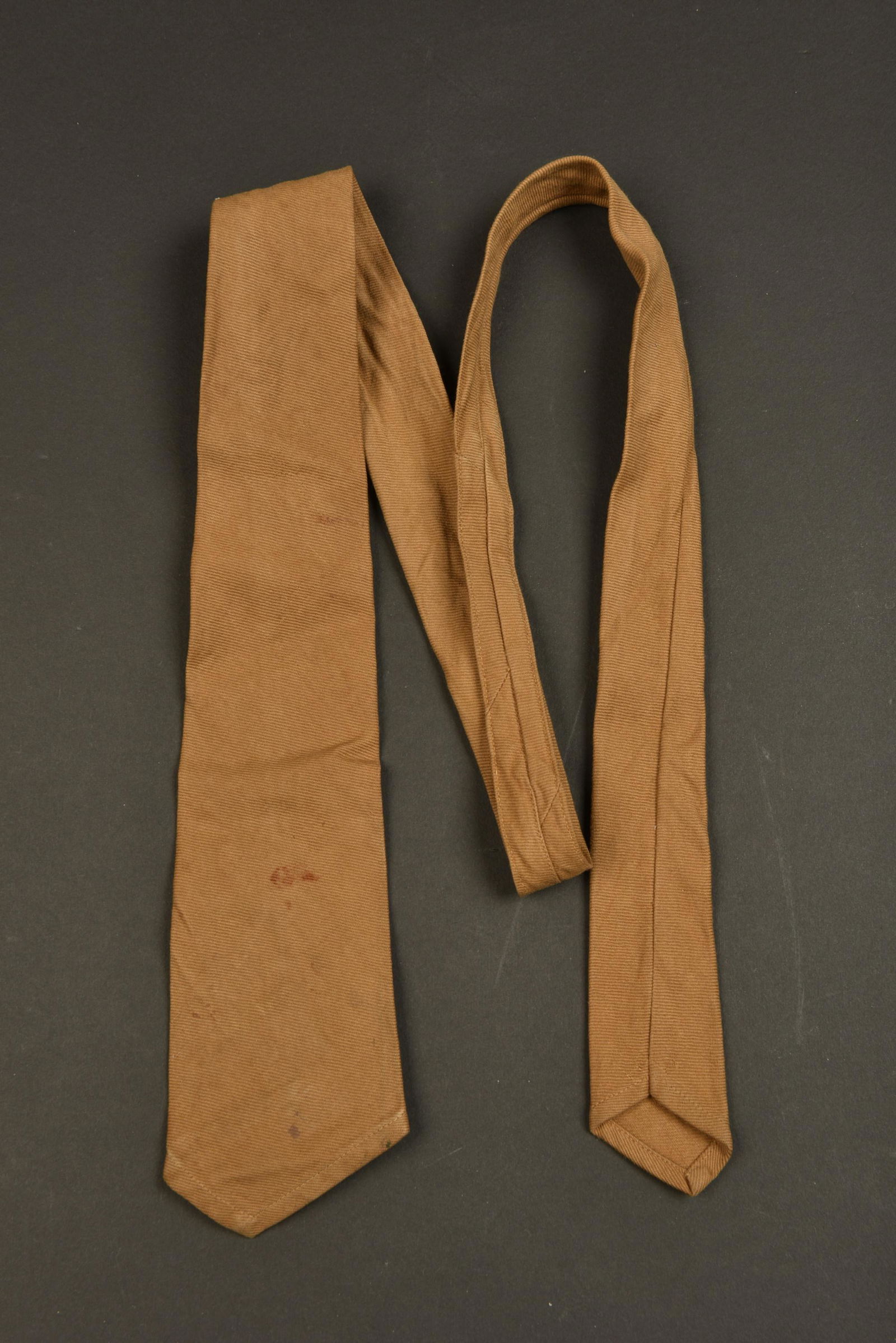 Cravate NSDAP. NSDAP Tie: Cravate NSDAP. En tissu coton marron. Etiquette RZM numero 027032, code fabricant257. A noter une certaine usure et patine de la piece, ainsi que quelques taches. Etat II+. NSDAP tie. In brown cotton