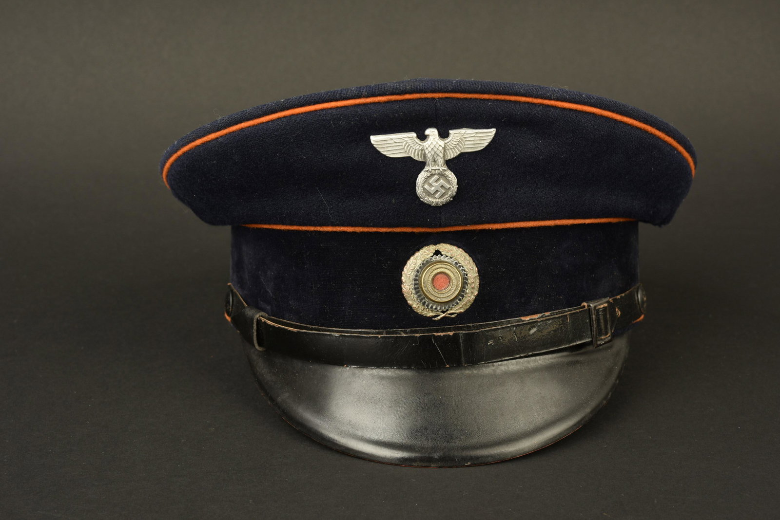 Casquette postier du Reich. Reich postman cap.: Casquette de postier du Reich. En drap bleu marine. Triple lisere orange faisant le tour de la coiffure. Aigle et cocarde metalliques. Les insignes n'ont pas ete demontes, afin de verifier les pattes 
