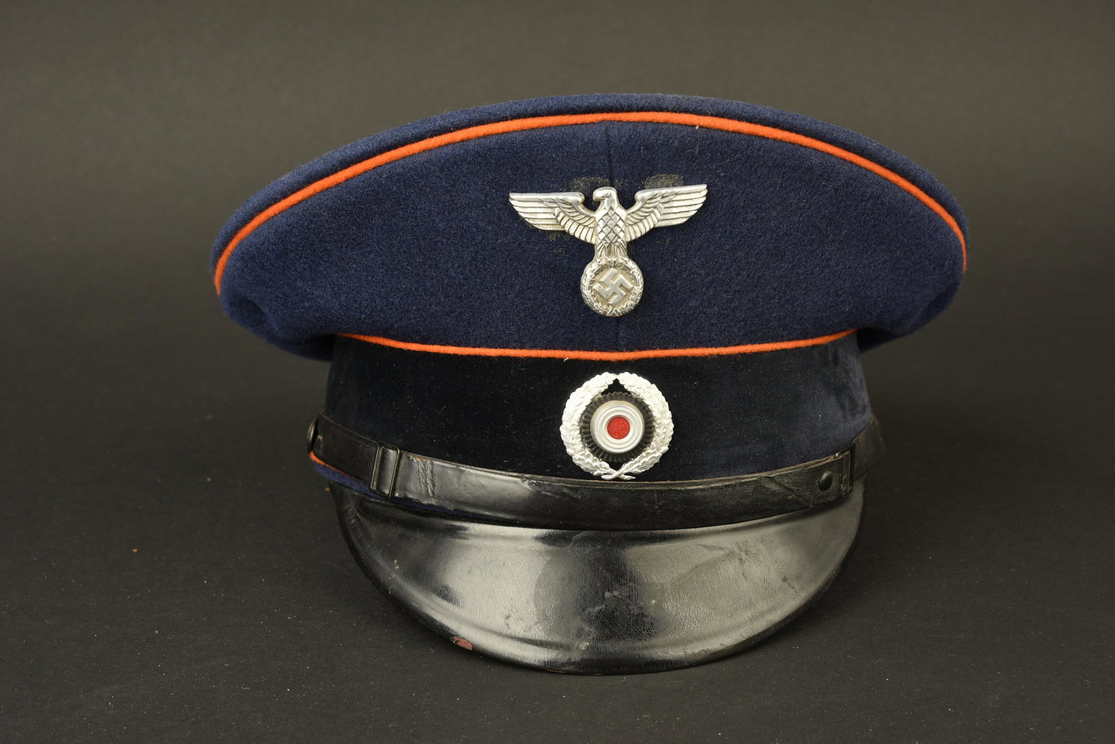 Casquette postier du Reich. Reich postman cap.: Casquette de postier du Reich. En drap bleu marine. Triple lisere orange faisant le tour de la coiffure. Aigle et cocarde metalliques. Trace de col au niveau de l'aigle. Les insignes n'ont pas ete dem