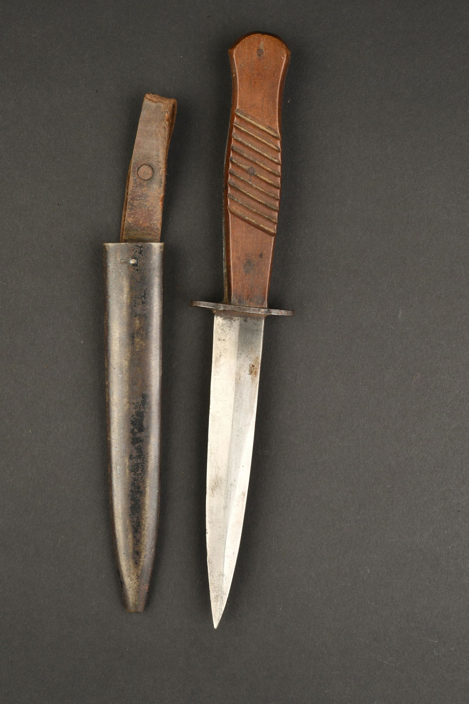 Poignard de tranchee. trench dagger: Poignard de tranchee, manche en bois strie, lame a deux tranchants, sans marquage visible. Fourreau en metal sans bouterolle avec reste de peinture d origine, passant en cuir present, patte de fermetu