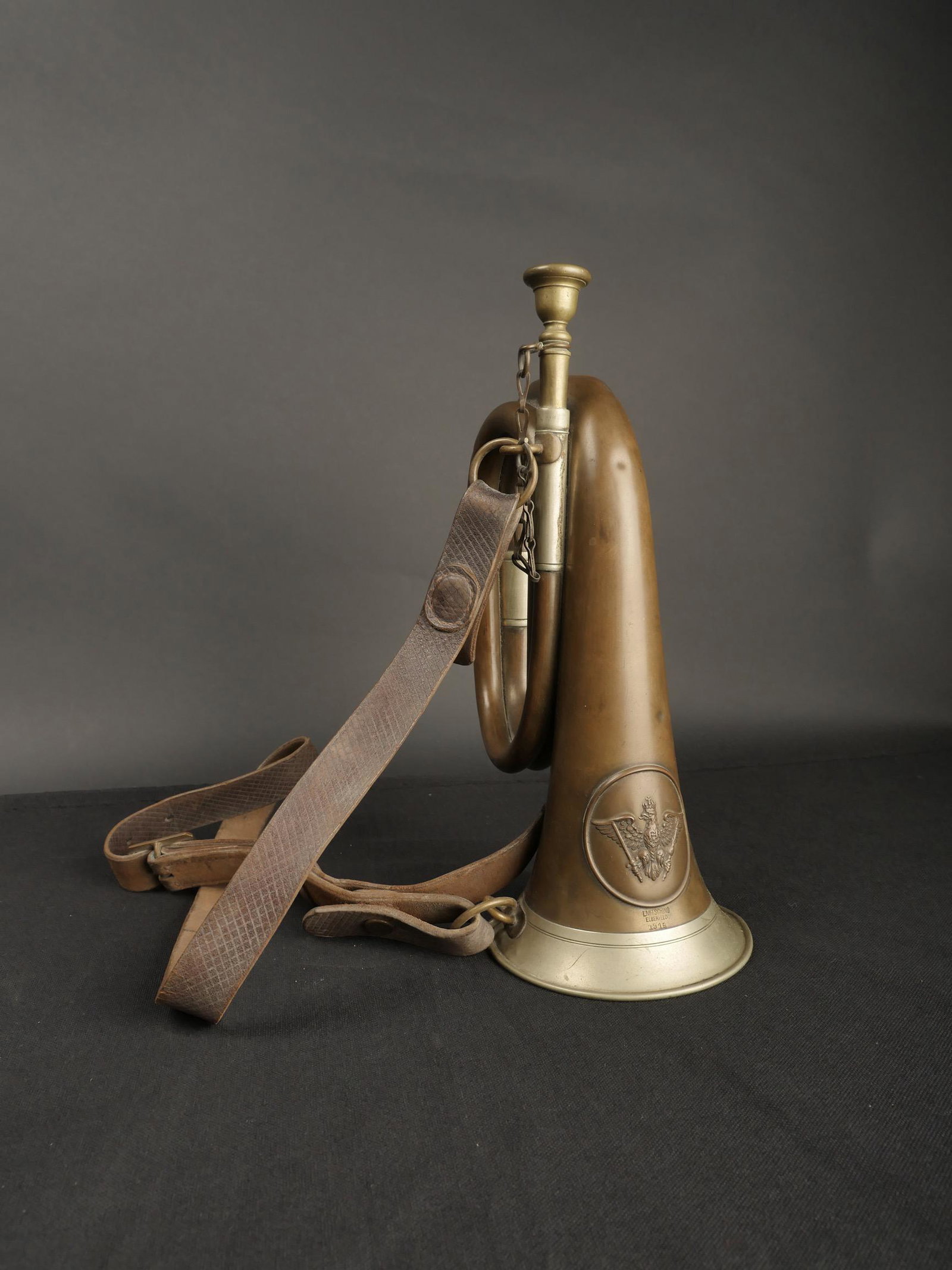 Buggle WWI.: Buggle allemand WWI. En laiton, et metal. Embout present. Bel insigne en relief. Fabrication L Mitsching Elberfeld 1915. Courroie en cuir presente. Nombreuses bosses sur l ensemble de l instrument. A 