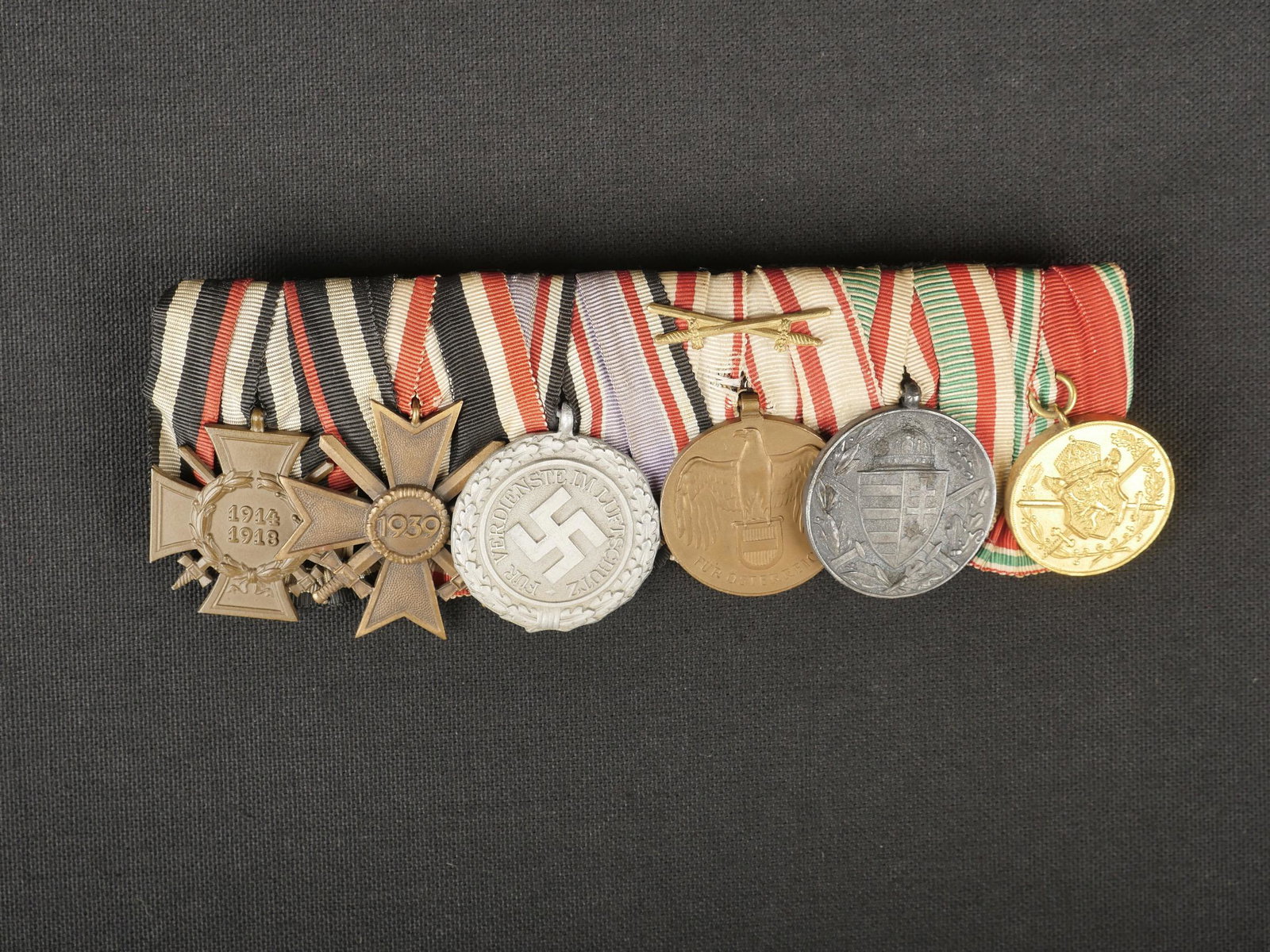 Barette de decoration pendante. Hanging decoration bar.: Barette de decoration pendante. Comprenant une medaille 1914/1918, une KVK avec glaives, une medaille Fur Verdienste im Luftschutz 1938, une medaille Fur Osterreich 1914/1918, une medaille Pro Deo Et 