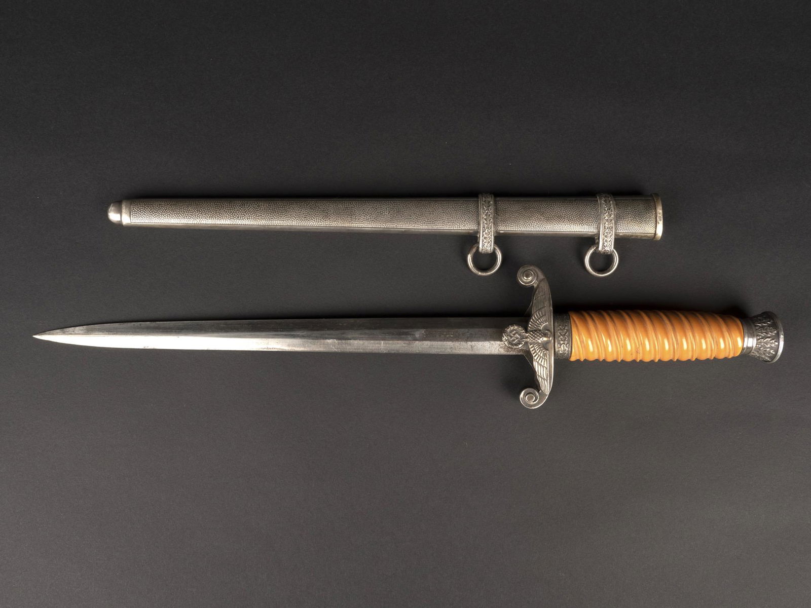 Dague officier Heer. German Heer Dagger.: Dague d officier de la Heer. Poignee en bakelite orange. Les parties metalliques sont de couleur argent fonce. Important jeu au niveau de la poignee. Lame complete, mais partiellement oxydee. Fabricat
