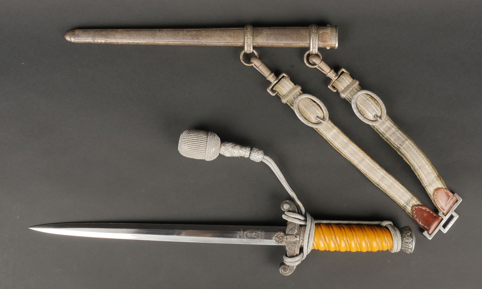 Dague officier Heer. German Heer Dagger.: Dague d officier de la Heer. Poigne en celluloid jaune. Garniture en metal couleur argent tres fonce. Dragonne presente et montee de maniere reglementaire. Fourreau en metal, complet. Tres belle lame,