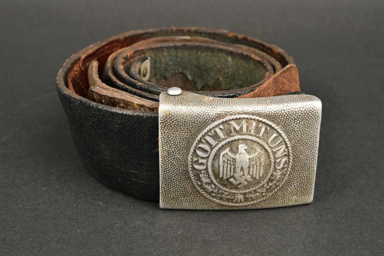 Ceinturon Heer. Heer belt.: Ceinturon Heer. Ceinturon en cuir noir, bouclerie en metal. Sans marquages visibles. Boucle de ceinturon en aluminium grenele, fabrication illisible, patte en cuir presente, marquage illisible. A note