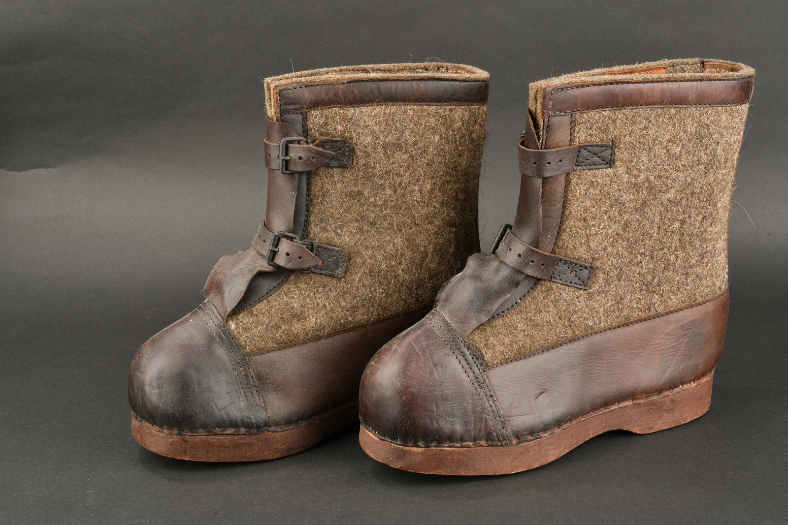 Bottes de garde. Guard boots.: Bottes de garde. En epaisse feutrine Feldgrau et cuir, fortement graisse. Semelles en bois. Paire homogene. Marquages presents mais illisibles. Datees 1942. A noter une certaine usure et patine de la 