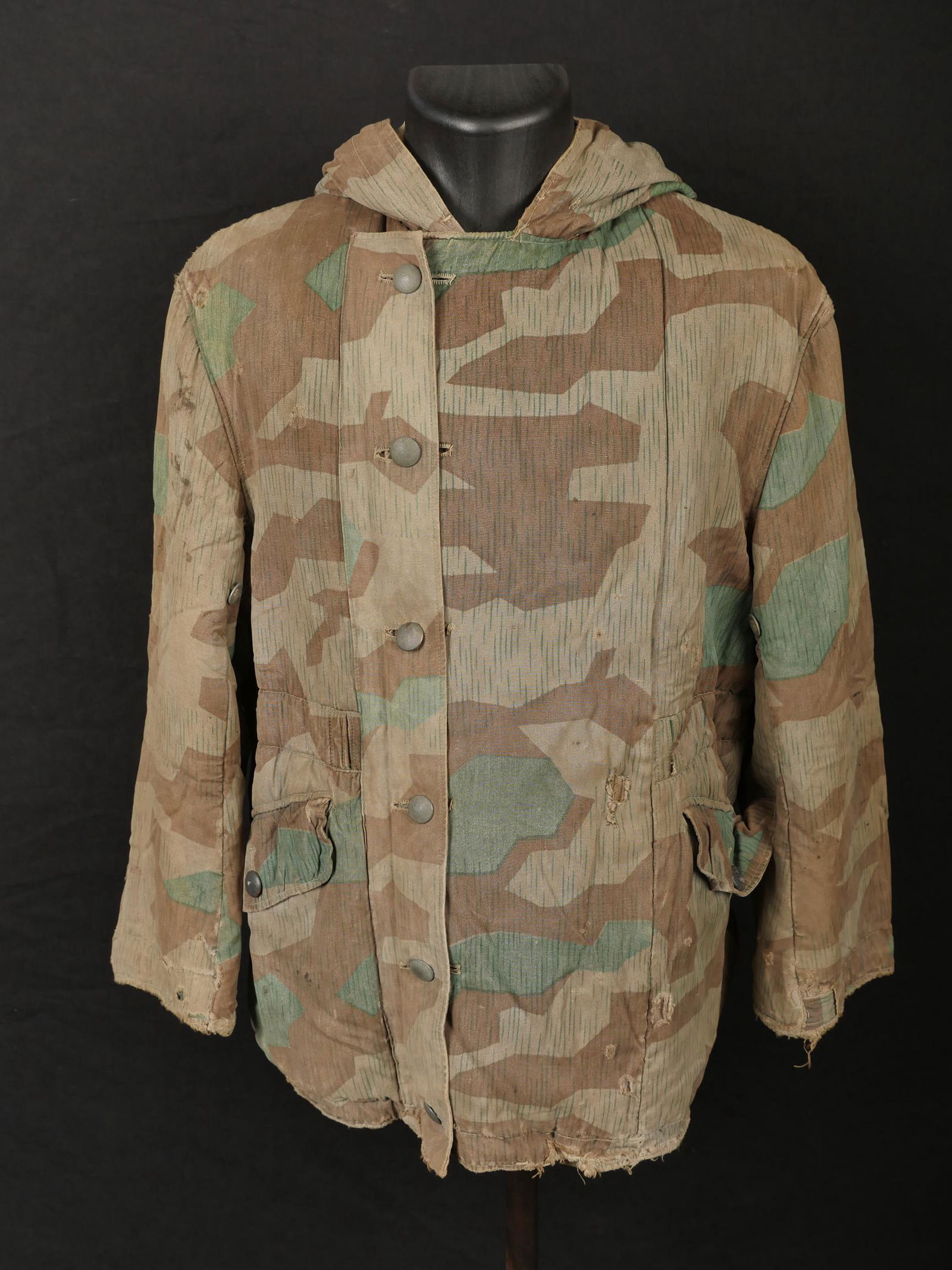 Parka camoufle. Camouflaged parka: Parka camouflee. En tissu camoufle eclat, reversible en tissu coton blanc. La majorite des boutons et des sangles sont presents. Sans marquages visibles. A noter une certaine usure et patine de la pie