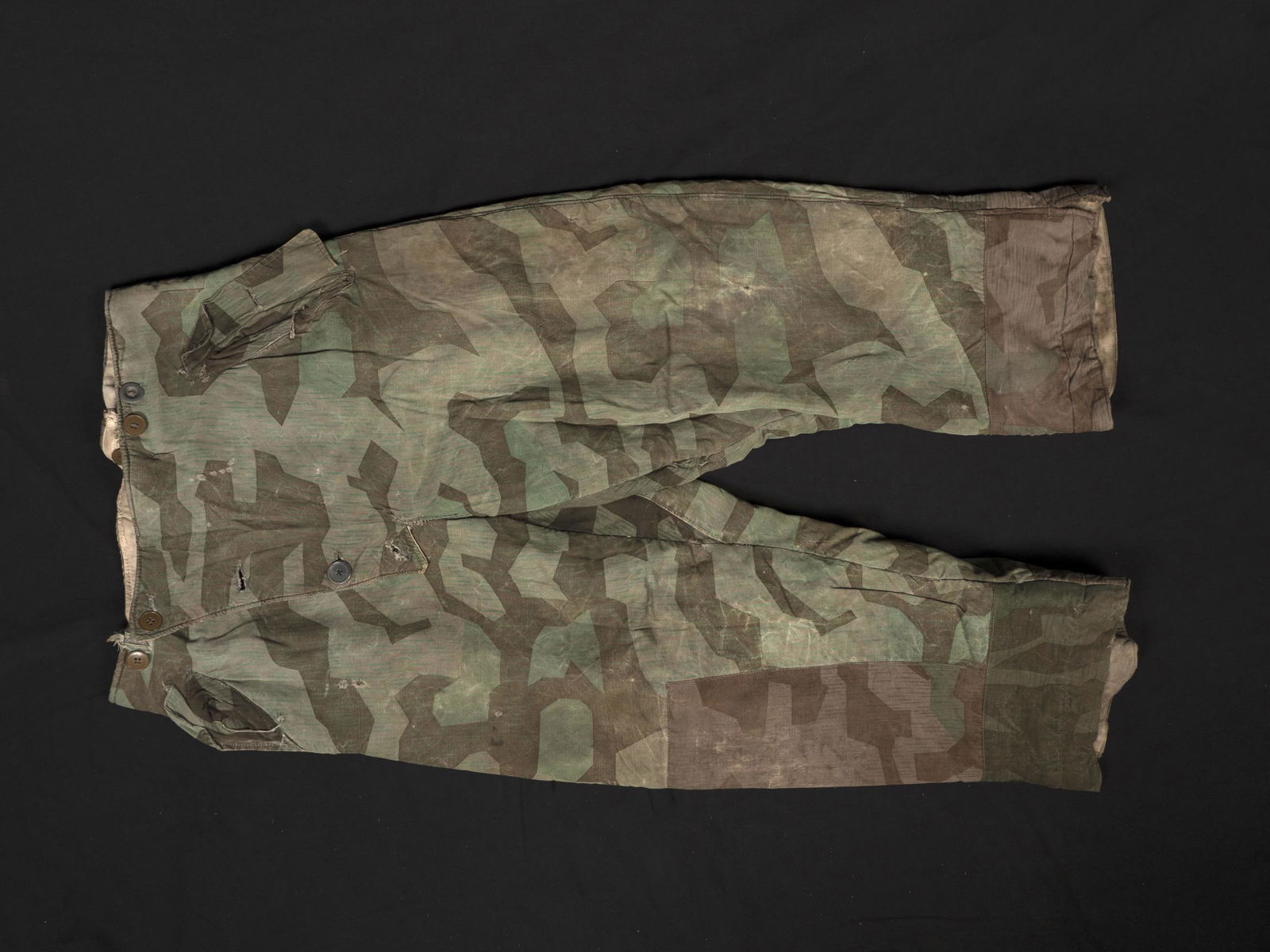 Pantalon camoufle. Camouflage pants.: Pantalon reversible camoufle. En tissu camoufle eclat, reversible en tissu coton blanc. La majorite des boutons et des sangles sont presents. Sans marquages visibles. A noter une certaine usure et pat