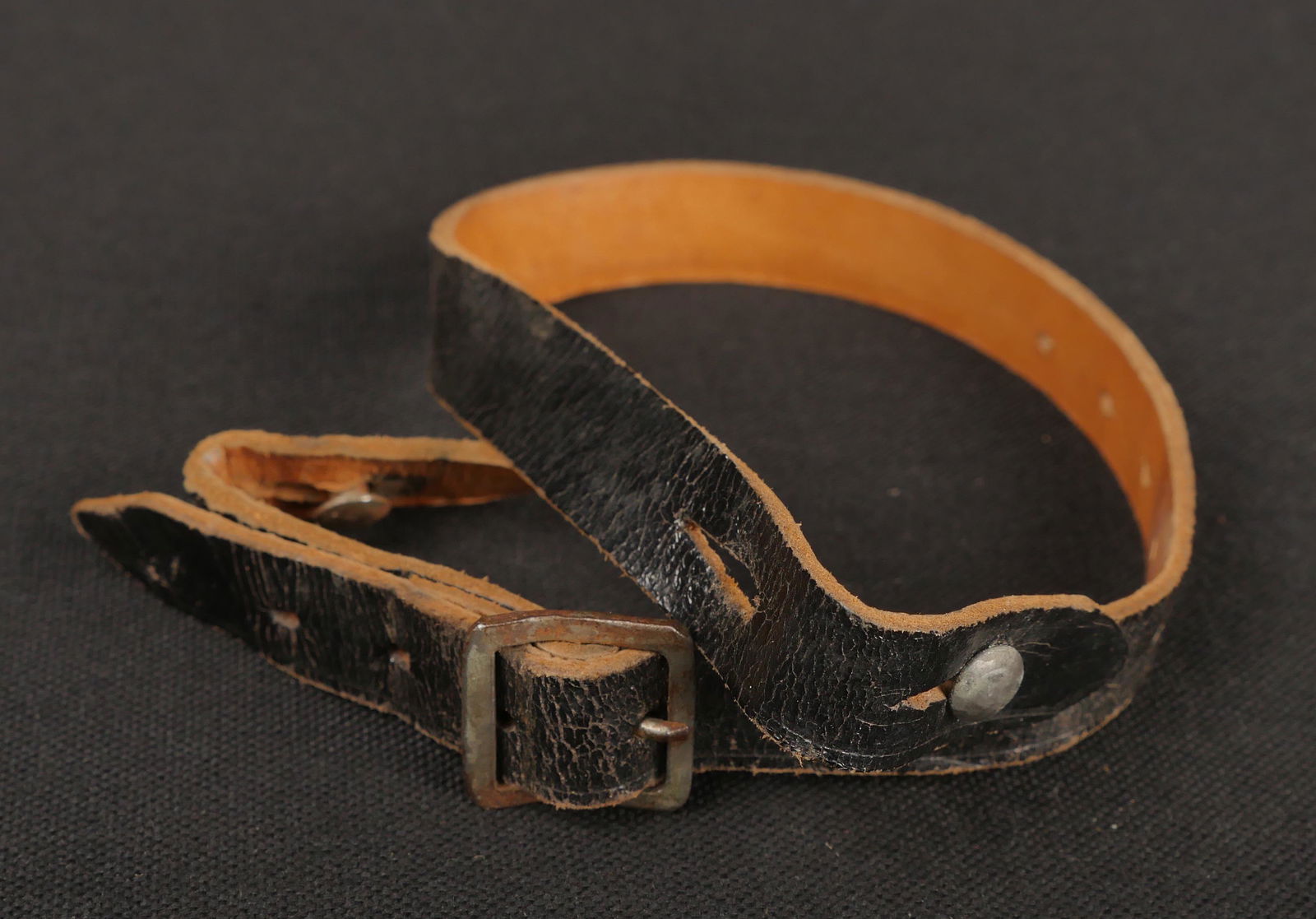 Jugulaire de casque allemand. German helmet chinstrap.: Jugulaire de casque allemand. En epais cuir noir. Bouclerie en metal. Les tetons de fixation sont presents. Douze crans de reglage. Fabrication FTB 4. A noter une legere usure et patine de la piece. E