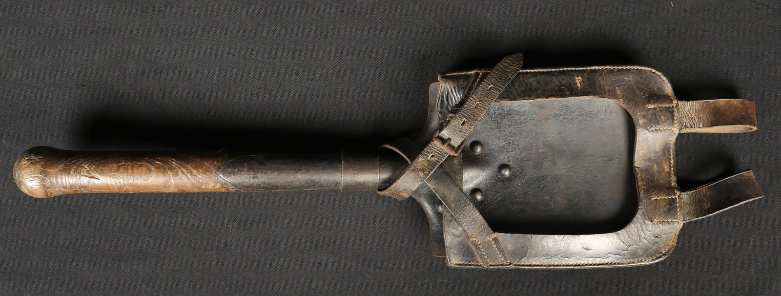 Pelle allemande. German shovel: Pelle allemande. Manche en bois, partie m etallique repeinte. Sans marquages visibles. Un rivet arri ere d efait. Housse en cuir noir, toutes les sangles sont pr esentes. Nom du fabricant illisible, m