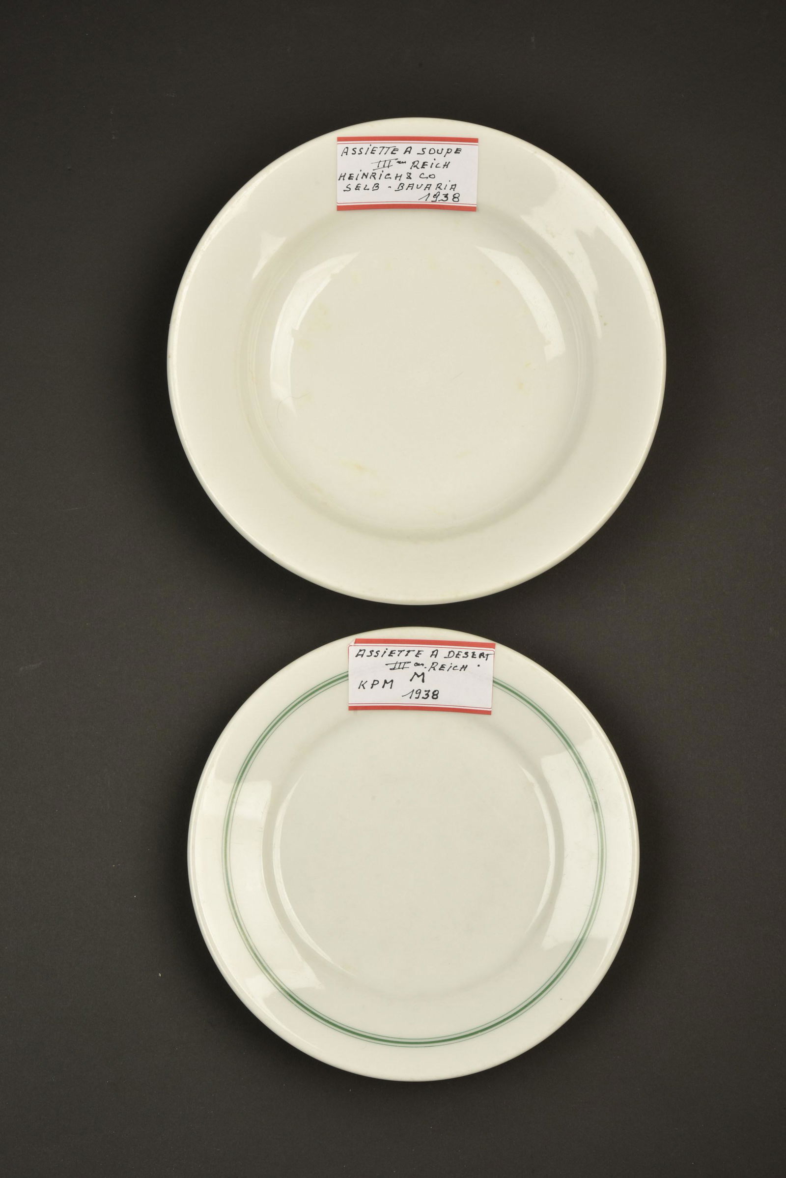Vaisselle allemande. German tableware.: Vaisselle allemande. Comprenant une assiette en porcelaine blanche, lisere vert du mess des officier, fabrication KPM 1938. Une assiette en porcelaine blanche, fabrication Heinrich 1938, modele pour l