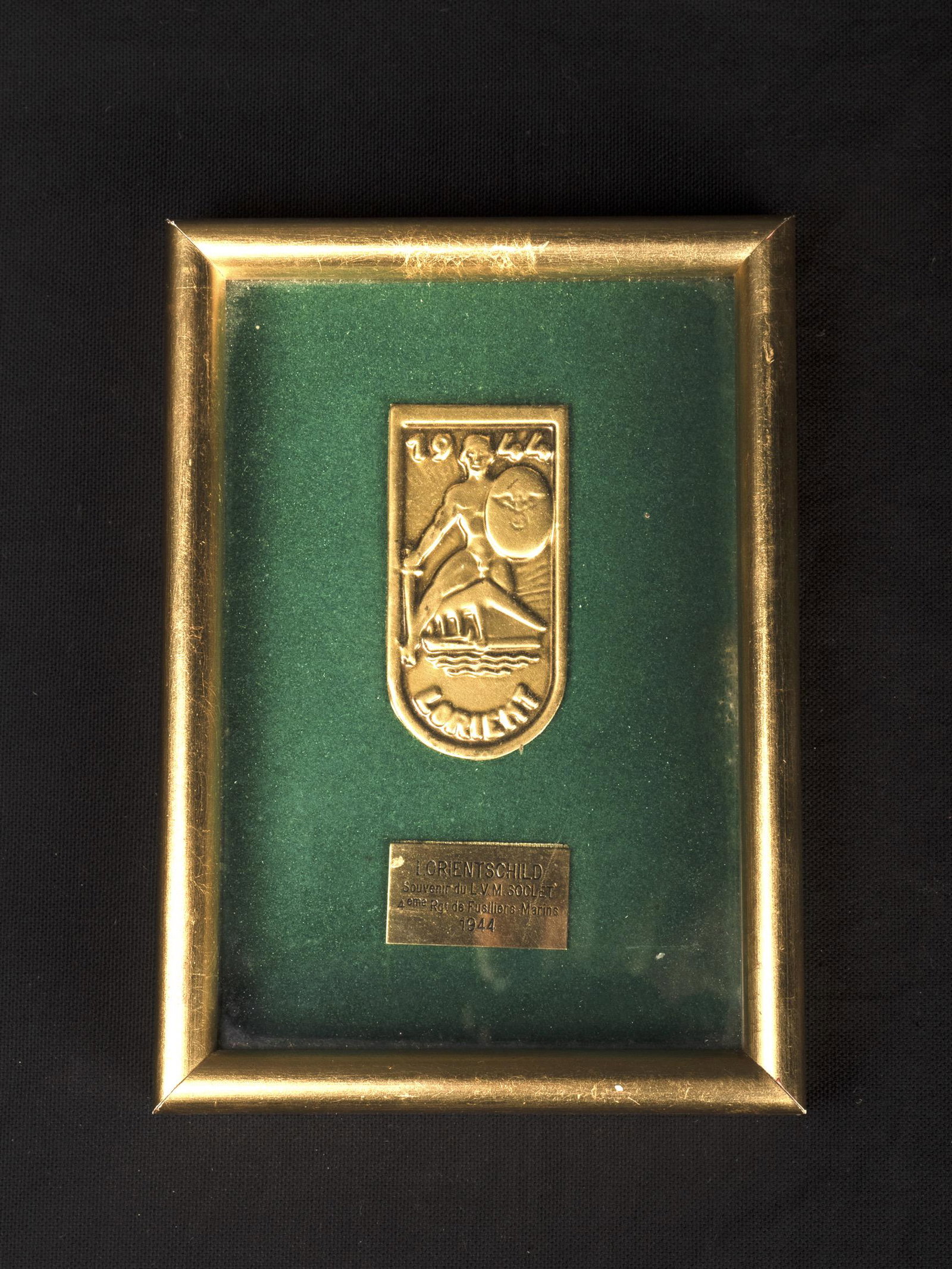 Lorient Schild.: Lorient Schild. En m etal embouti, type boite de conserve. Sous cadre moderne. Le cadre n a pas et e ouvert afin de v erifier le dos de l insigne. Plaquette en laiton marqu ee Souvenir du LVM Soclet 4