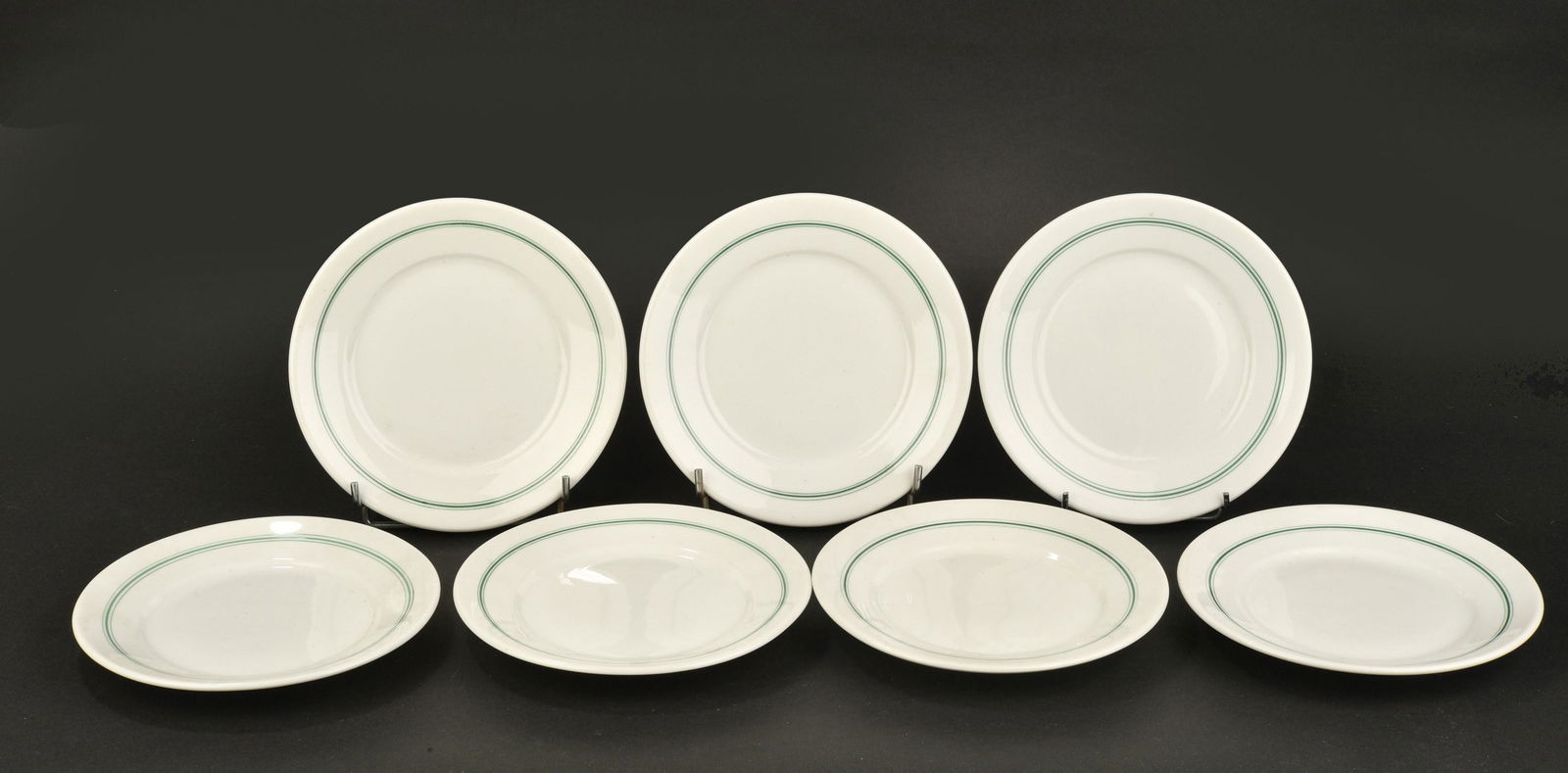 Petites assiettes Kriegsmarine. Small plates Kriegsmarine.: Petites assiettes Kriegsmarine. Sept petites assiettes en porcelaine blanche, liser e vert. Mod ele pour les officiers. Fabrication KPM 1941, KPM 1942, . Diam etre 16 cm. A noter une certaine usure et