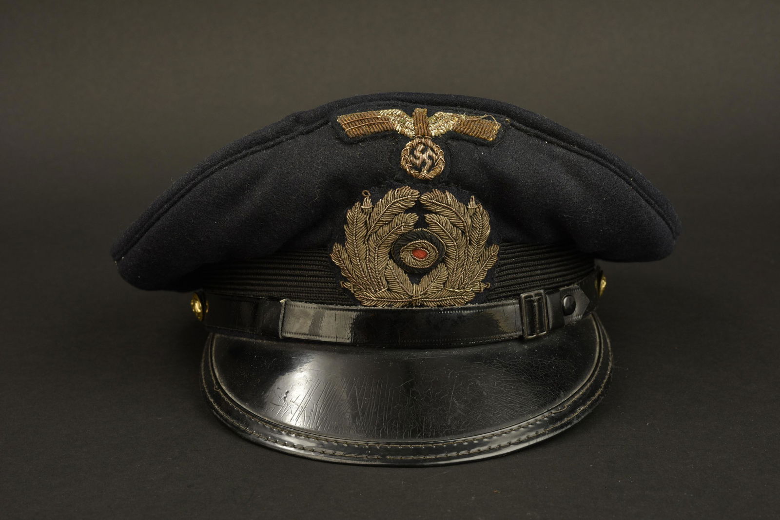 Casquette KM. Kriegsmarine cap: Casquette Kriegsmarine. Modele de casquette pour officier marinier. En drap noir. Aigle et cocarde en cannetille dore. Fausse jugulaire complete. Interieur double en satinette bleu. Mica manquant. Ban