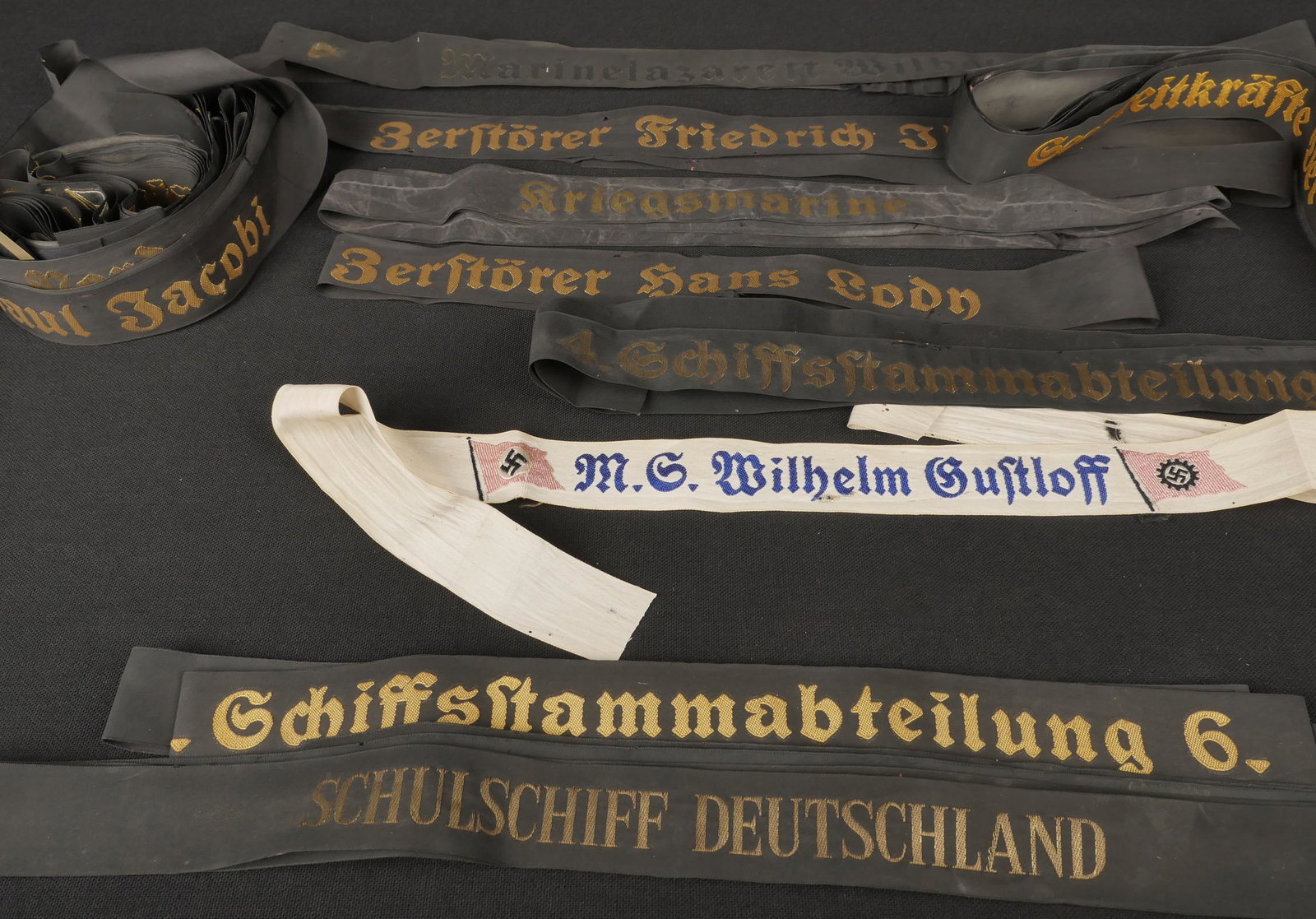 Bandes de bachi KM. KM tarpaulin strips.: Bande de bachi Kriegsmarine. Comprenant une bande marqu ee Marinesanitatschule, longueur 51 cm. Une bande Zerstorer Hans Lodn, longueur 76 cm. Une bande 2 Marineunternoffizierlehrabteilung, longueur 5