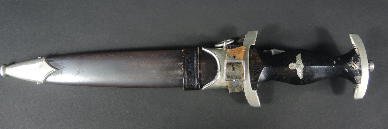 Dague SS 33. SS dagger: Dague modele 33 de la SS. Garnitures metalliques. Poignee en bois noir, comportant de nombreux accidents. Aigle metallique monte d'origine. Runes SS refixees. Fourreau complet, couleur noire a 30%, fo