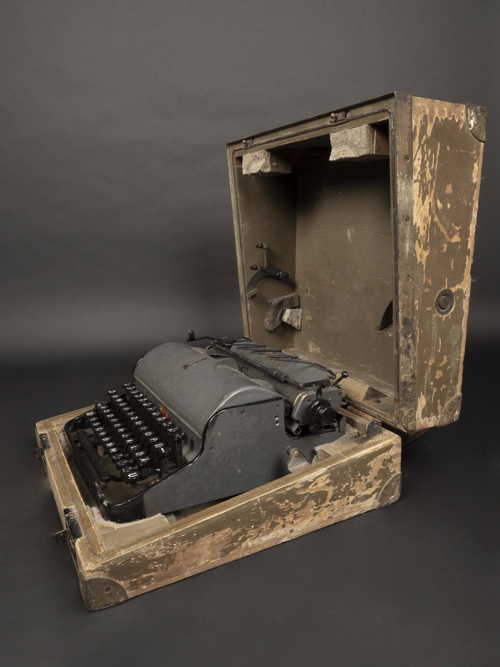 Machine a ecrire SS. Typewriter Waffen SS.: Machine a ecrire SS en caisse d'origine. Caisse en bois, peinture Feldgrau a 40%. Tous les crochets de fermeture sont presents. Poignee de transport en metal. Renforts en metal sur les coins de la cai