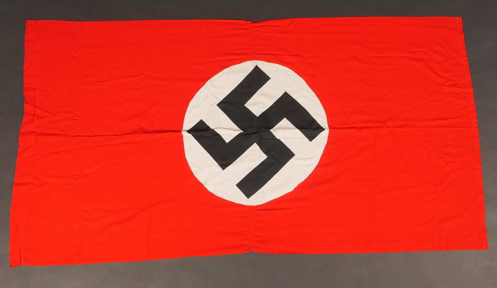 Drapeau allemand. German flag.: Drapeau allemand. En tissu coton rouge. Partie centrale rapportee, embleme national imprime. Biface. Sans marquages visibles. Dimensions 76 x 142 cm. A noter une certaine usure et patine de la piece, 