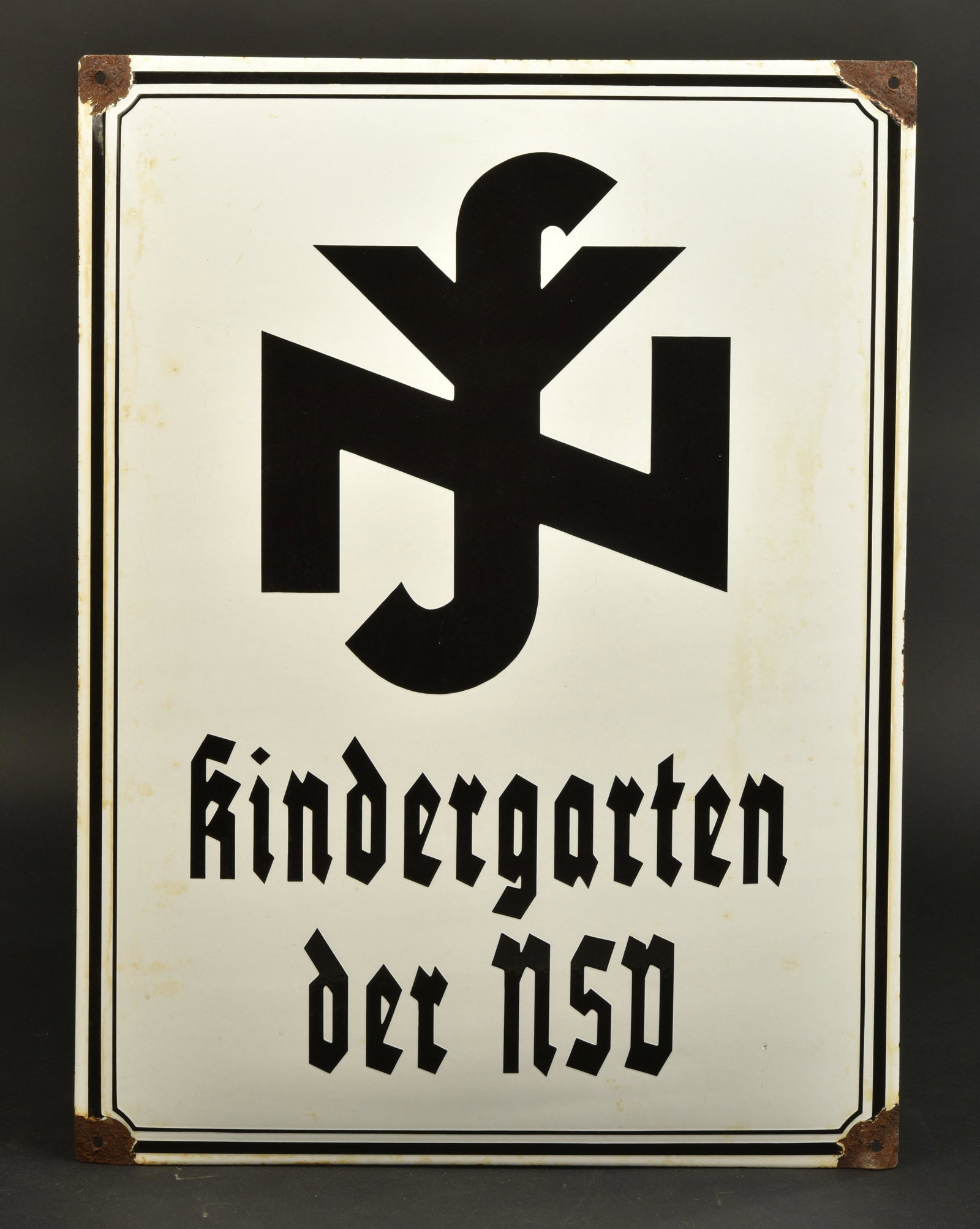 Plaque NSD. NSD Plate: Plaque NSD. En metal emaille blanc, bordure noire. Quelques manques dans l'email. Marquages Kindergarten der NSD. Dimensions 45 x 61 cm. A noter une certaine usure et oxydation de la piece. Etat II+.