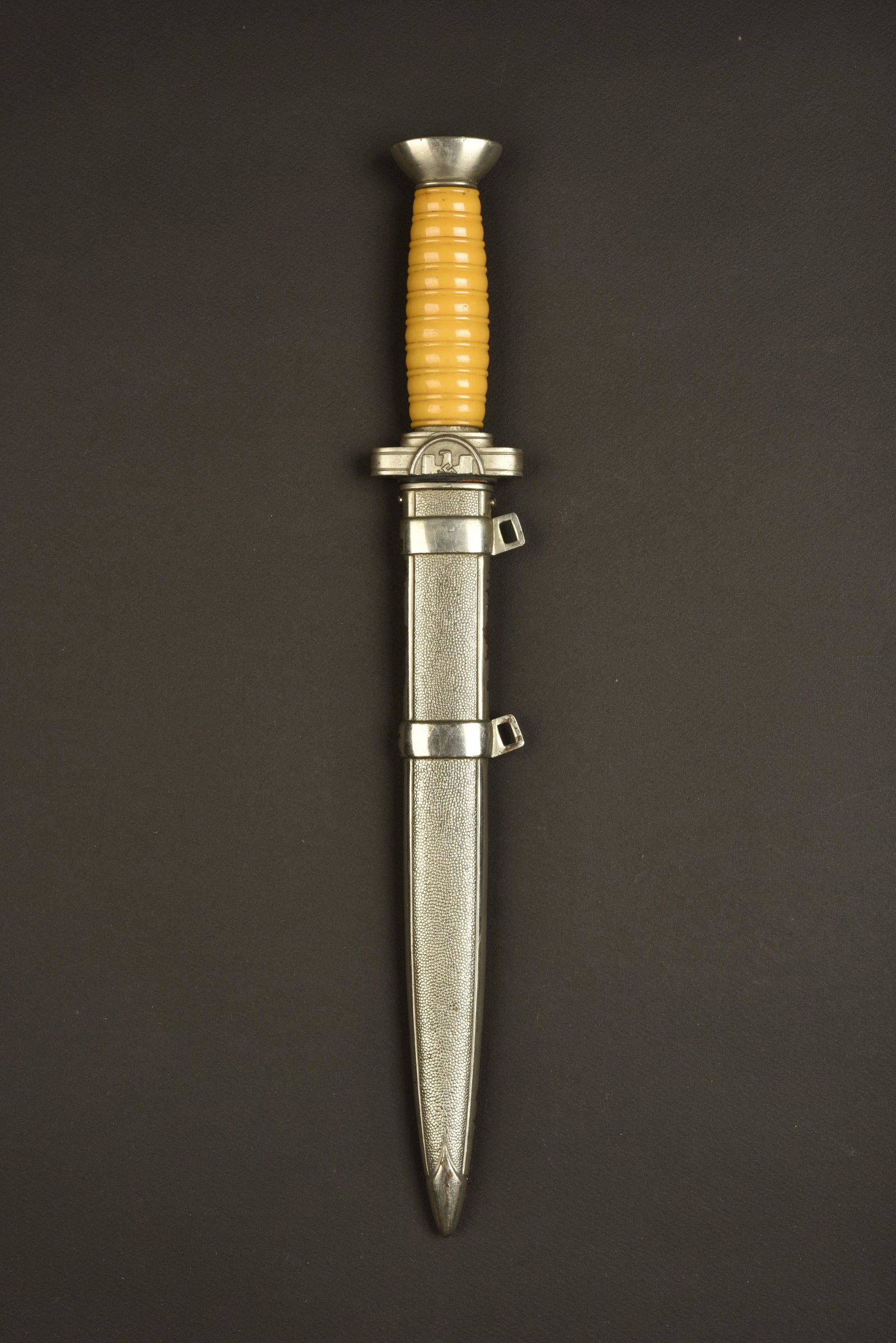 Dague officier DRK. DRK dagger.: Pommeau presentant un certain jeu, vis presentant des traces de demontage. Poignee en matiere plastique jaune. Ecu de l insigne national coupe en deux, donc incomplet. Lame complete dans sa longueur,