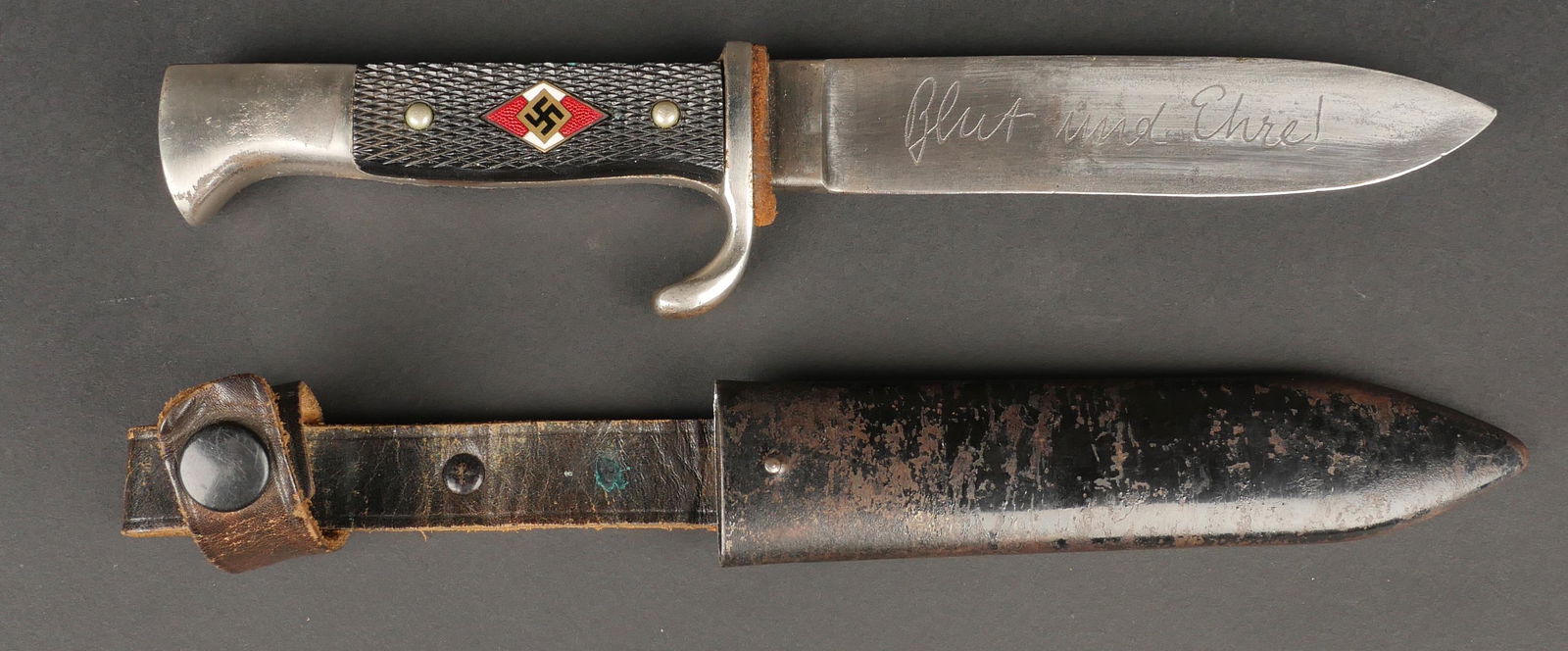 Couteau de marche HJ. Hitlerjugend dagger.: Couteau de marche Hitlerjugend. Plaquettes en bakelite rivetes d'origine. Insigne monte d'origine mais presentant un certain jeu. Email intact. Lame en bon etat, disposant de la devise Blut une Ehre.