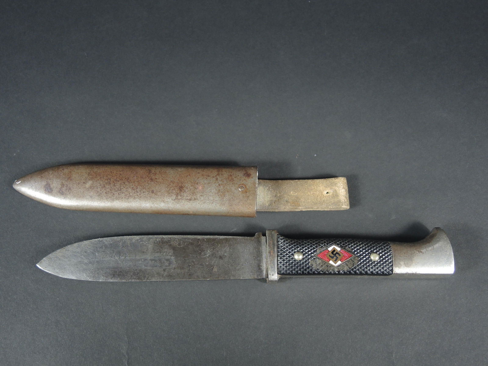 Couteau de marche HJ. Hitlerjugend dagger.: Couteau de marche Hitlerjugend. Plaquettes en bakelite rivetes d'origine. Insigne monte d'origine mais presentant un certain jeu. Email intact. Lame en bon etat, disposant de la devise Blut une Ehre.