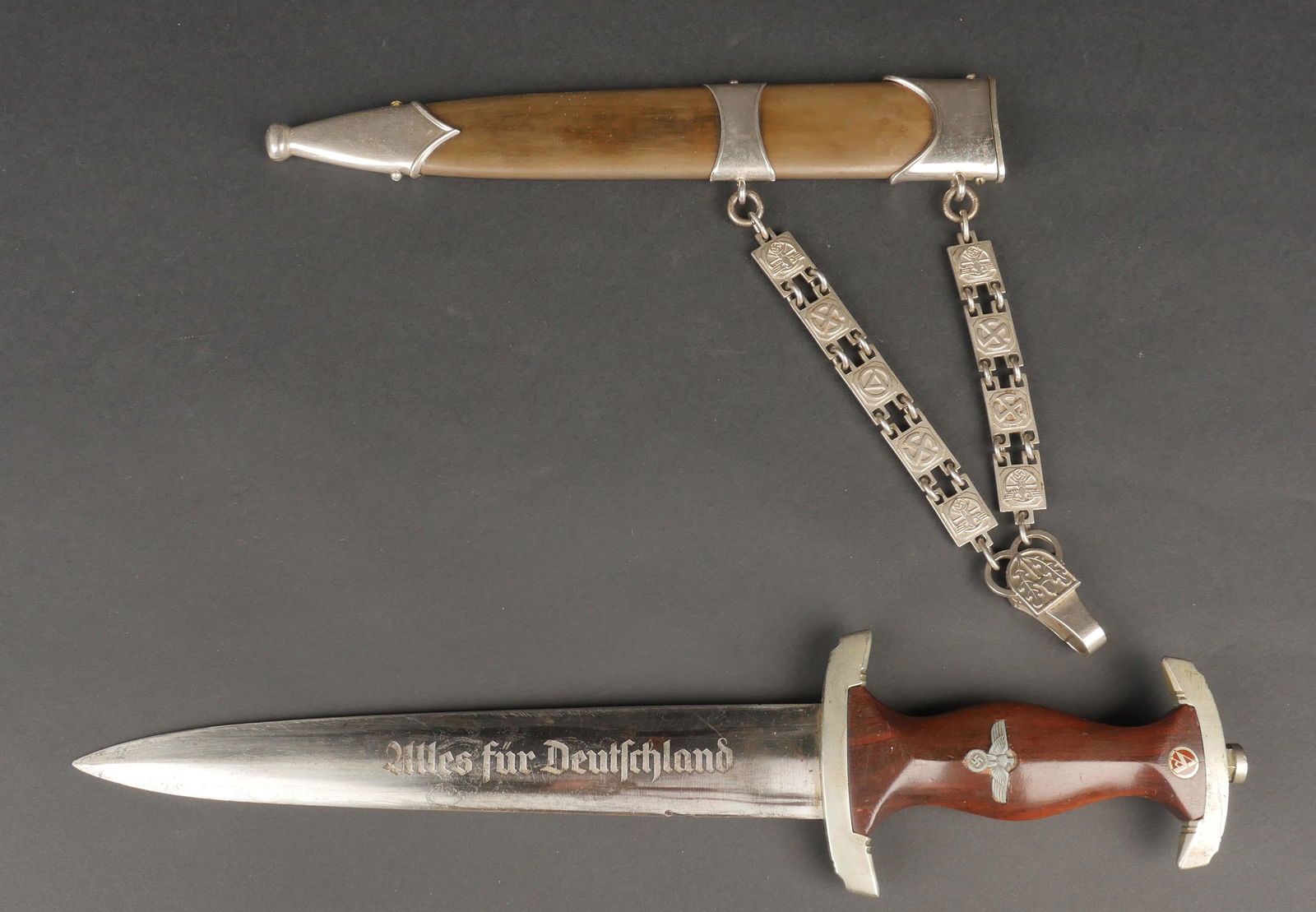 Dague NSKK. NSKK Dagger.: Dague NSKK a chainette. Modele 1933 modifie 1939. Poignee en bois marron avec sigle SA en maillechort emaille. Garde d'un modele different de la dague, disposant de la lettre Wf pour le NSKK Grupp Wes