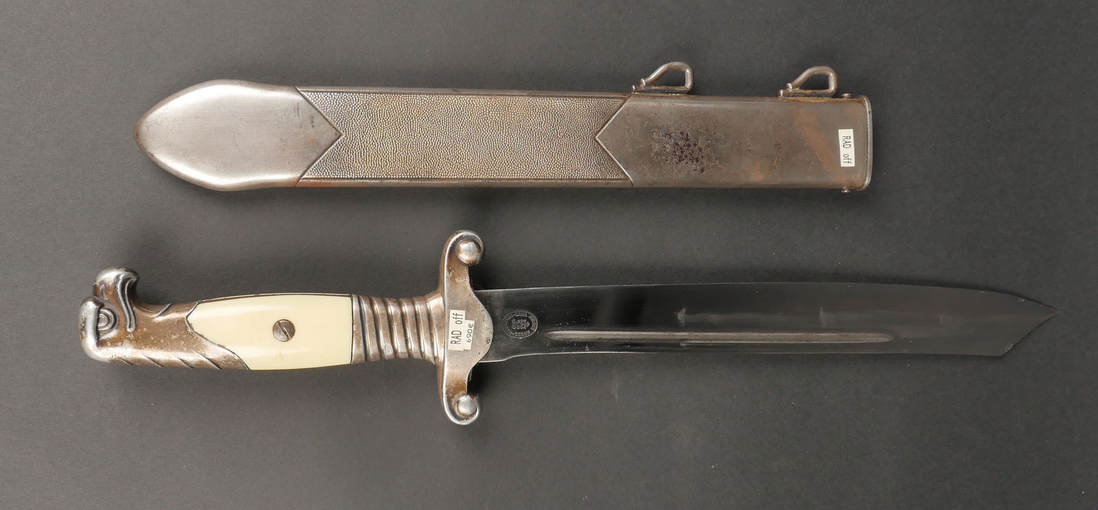 Dague officier RAD. German RZD dagger.: Dague officier RAD. Modele 1937. Plaquette d'origine presentant quelques fissures. Poignee et tete d'aigle en aluminium argente. Argenture presente a 95%, non cloquee. Lame tres fine en tres bon etat.