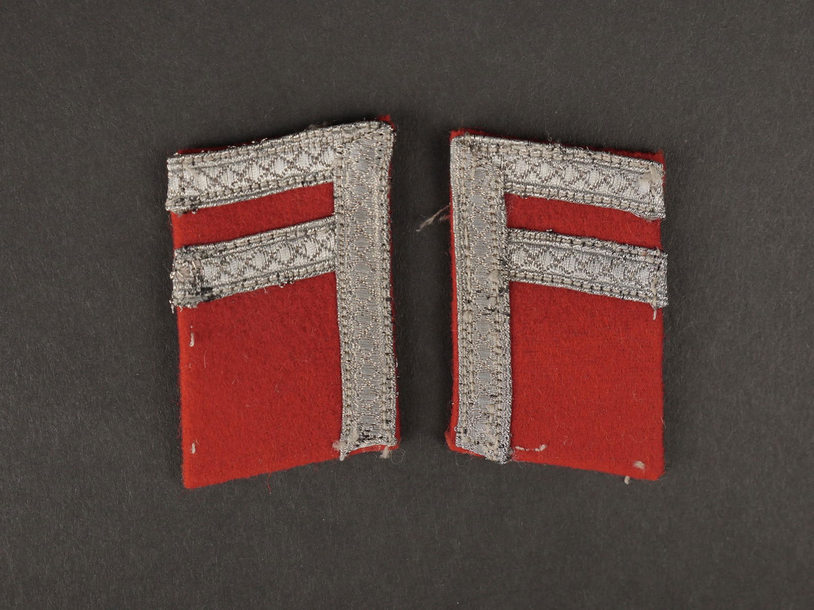 Patte de col. Collar tabs.: Pattes de col de volontaires etrangers. En drap rouge, galon argent. Paire homogene. Traces de colle au dos. A noter une certaine usure et patine des pieces. Etat II+. Plus de photos sur aiolfi.com. C