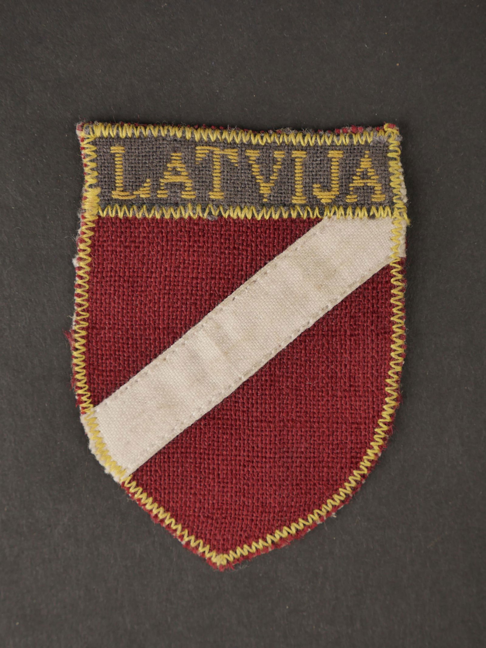 Insigne de manche Latvia.Latvia sleeve badge.: Insigne de manche des volontaires letton dans la Heer. Modele brode, jamais monte, couture jaune faisant le tour de l insigne. Dos de la piece double en epais tissu ecru. Mention Latvija au niveau de