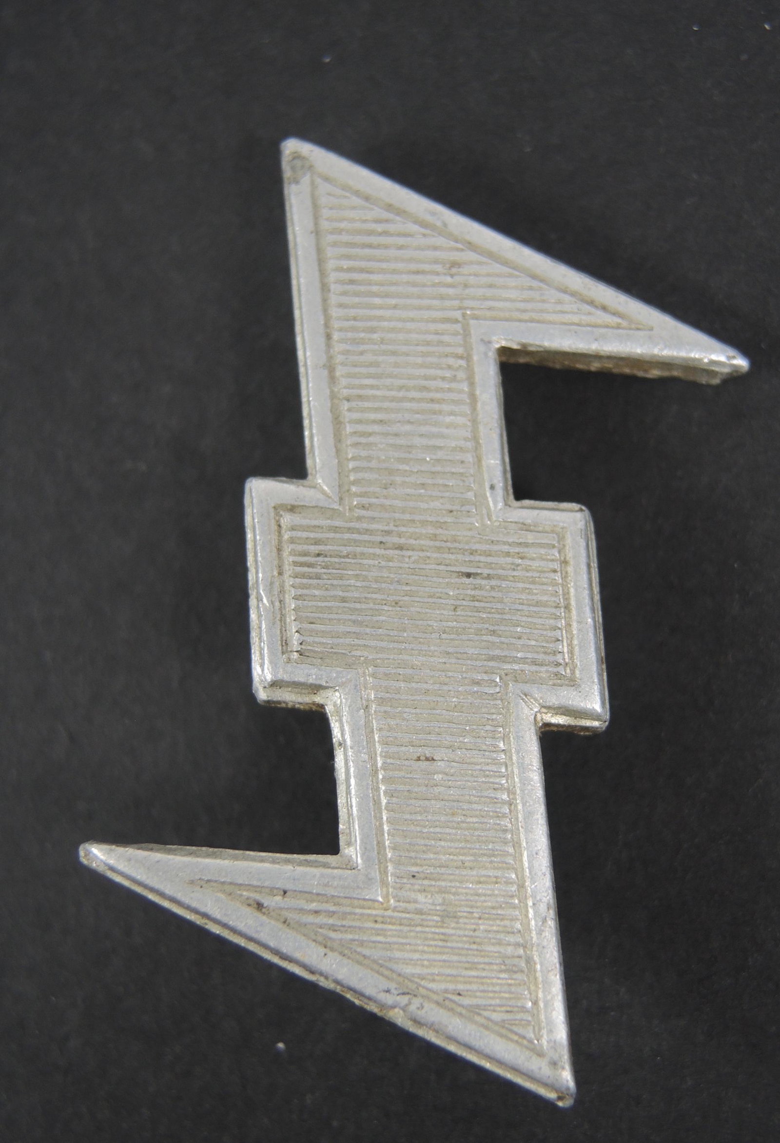 Rune du loup. Wolf Rune.: Rune du loup. Insigne de coiffure de la SS Neerlandaise. En aluminium, toutes les attaches sont presentes. A noter une certaine usure et patine de la piece. Etat II+. Rune of the wolf. Badge of headge