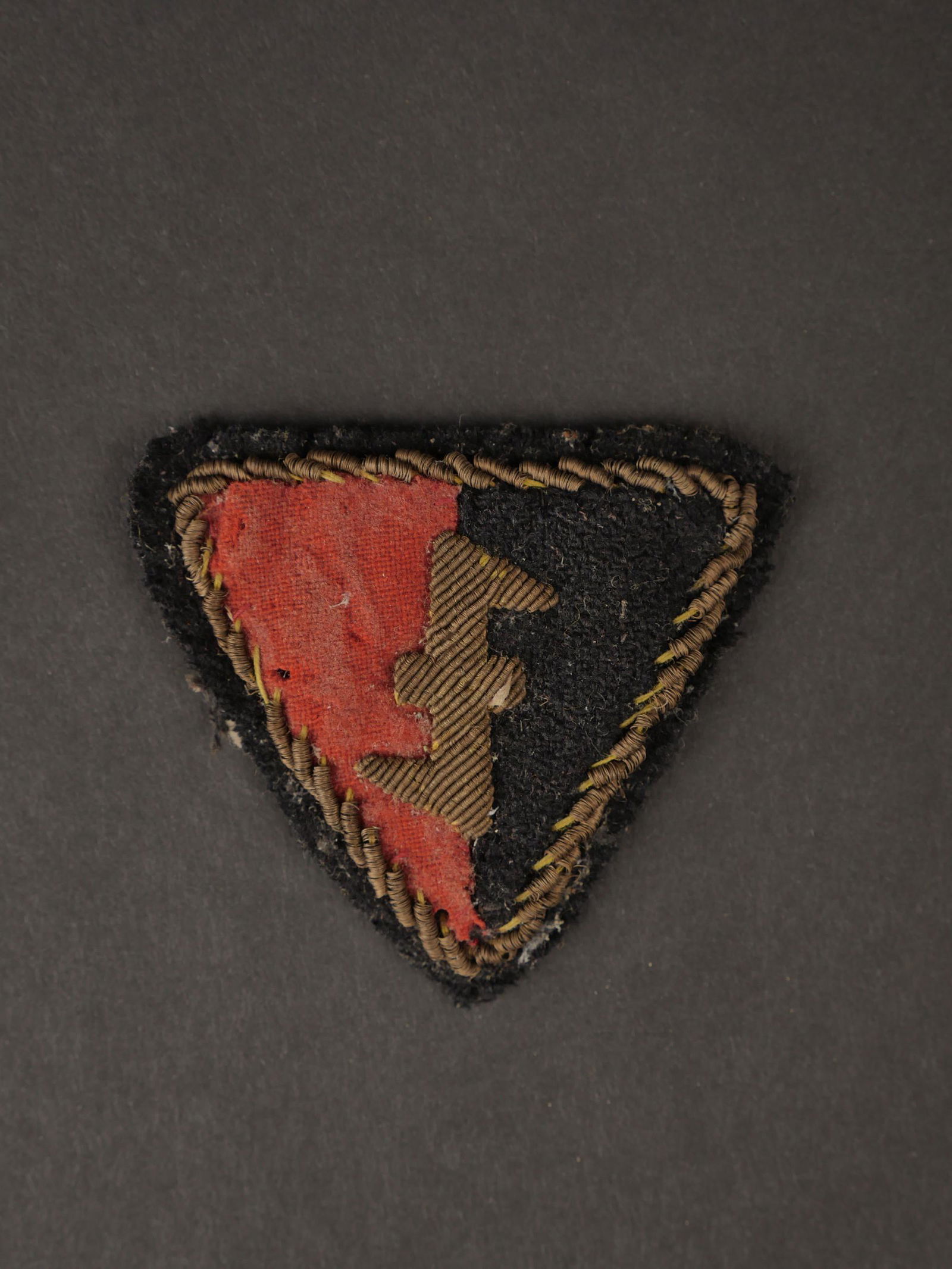 Insigne de coiffure NSB. Badge of the Dutch youth.: Insigne de coiffure du NSB. Modele en drap rouge et noir, monte sur fond noir. Insigne du NSB en cannetille or, ainsi que le galon faisant le tour de l insigne. Dos de l insigne double d un tissu coto