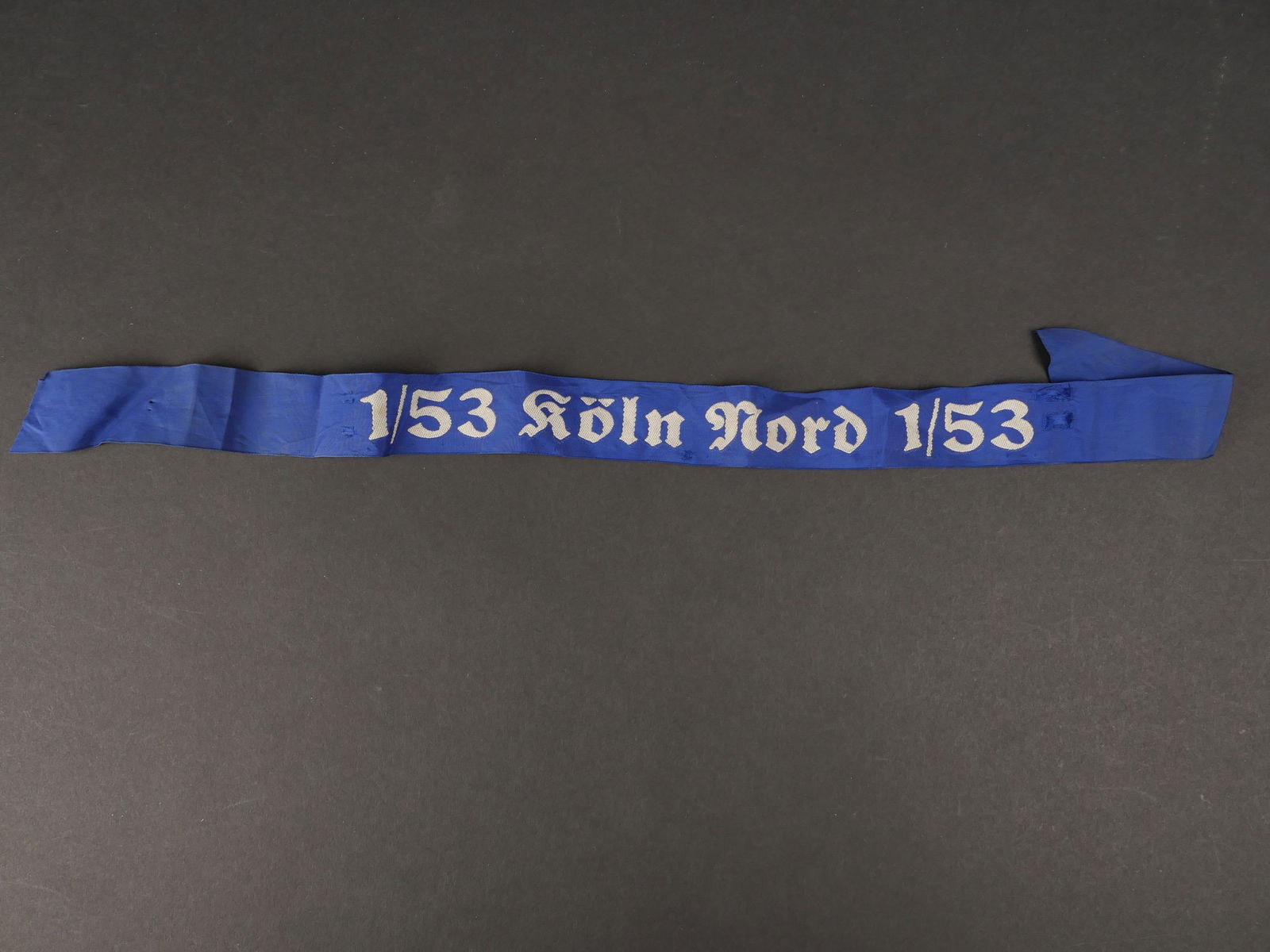 Bande de bachi HJ. HJ bachi band.: Bande de bachi Hitlerjugend Marine. En tissu bleu roi. Tissage en fil blanc, marque 1/53 Koln Nord 1/53. Longueur 59 cm. Quelques accrocs et marques d usures. A noter une certaine usure et patine de l