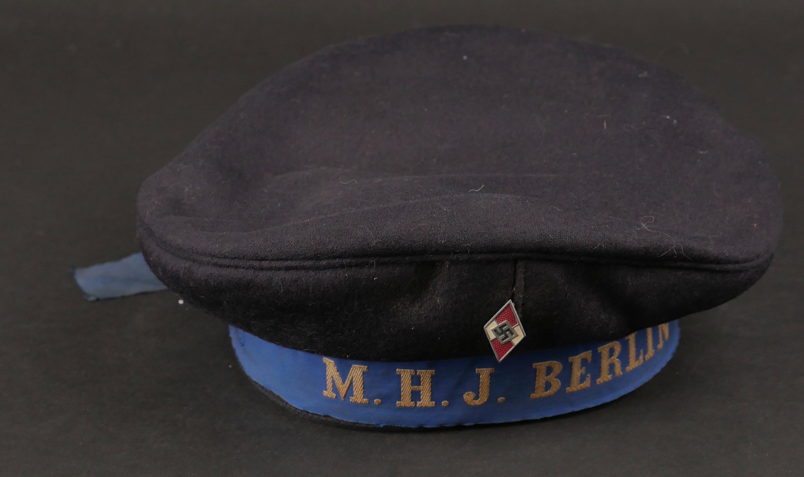 Bachi Hitlerjugend. Bachi Hitlerjugend.: Bachi Hitlerjugend. En drap noir. Insigne metallique Hitlerjugend, attache complete, fabrication RZM M1/103, correspondant au fabricant Carl Poellath Schrobenhausen. Bande de bachi en tissu bleu, brod