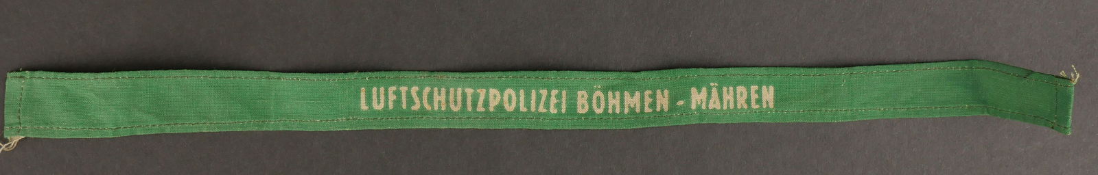 Bande de bras Luftschutz. Luftschutz arm band.: Bande de bras Luftschutz. En tissu coton vert, inscription imprimee Luftschutzpolizei Bohmen Mahren. Longueur 40 cm. A noter une certaine usure et patine de la piece. Etat II+. Arm band Luftschutz. Ma