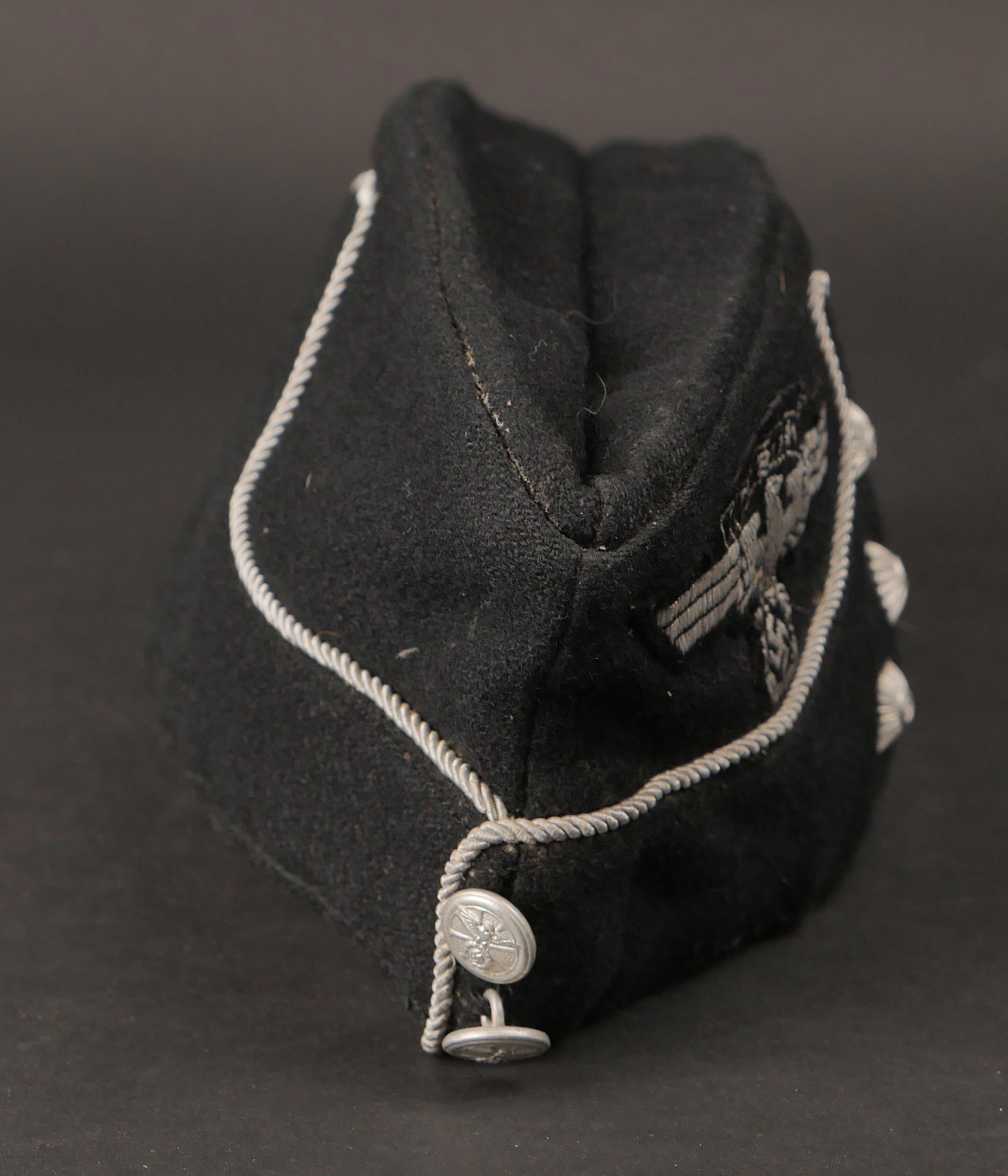 Calot NSKK. NSKK cap.: Calot d officier NSKK. En drap noir, lisere argent faisant le tour de la coiffure. Trois clous de grade. Deux boutons metalliques estampilles de l insigne NSKK, fabrication RZM M5/82, correspondant au