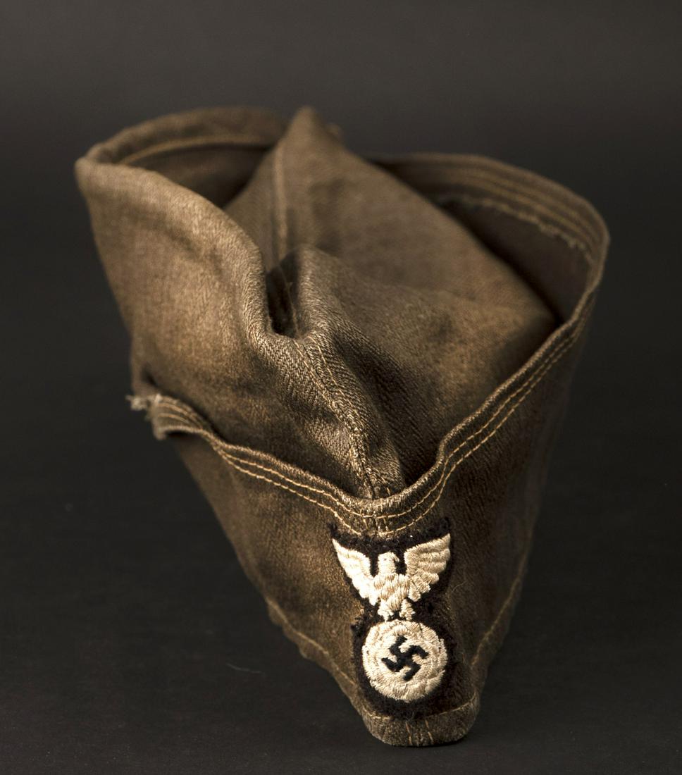 Calot type SA. SA type cap.: Calot type SA. En forte toile Feldgrau, nombreuses taches. Interieur double en tissu coton gris. Sans marquages visibles. Aigle type SA brode en fils blanc sur fond noir. Cousu main. A noter une certa