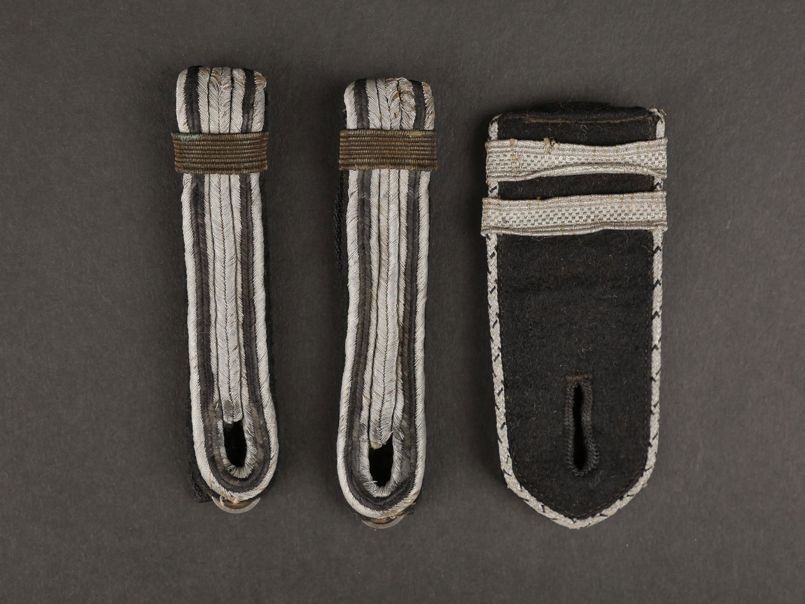 Pattes d epaule du Teno. Teno s shoulder legs.: Pattes d epaule du Teno. Paire homogene de pate d epaule en tissu noir et cannetille argent. Barette de grade en filigrane or. Grade de Hauptscharfuhrer. On y joint une epaulette en tissu noir, lisere