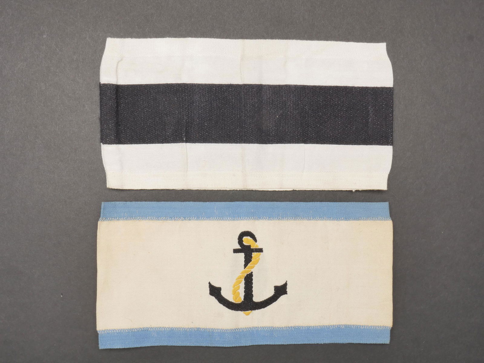 Brassard Kriegsmarine. Kriegsmarine armband.: Brassard Kriegsmarine. Comprenant un brassard de chef de la defense anti aerienne de la Marine, en tissu coton blanc, double galon bleu ciel, ancre de marine brodee. Un brassard en tissu coton blanc e