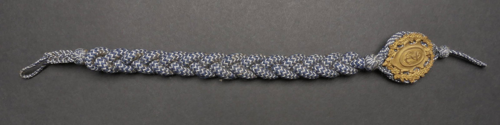 Cordon de tireur Kriegsmarine. Kriegsmarine shooting cord.: Cordon de tireur de la Kriegsmarine. Rare cordon. Tressage bleu marine et blanc. Les attache sont presentes. Insigne en metal dore. Dos de la piece double en drap bleu marine. A noter une certaine usu