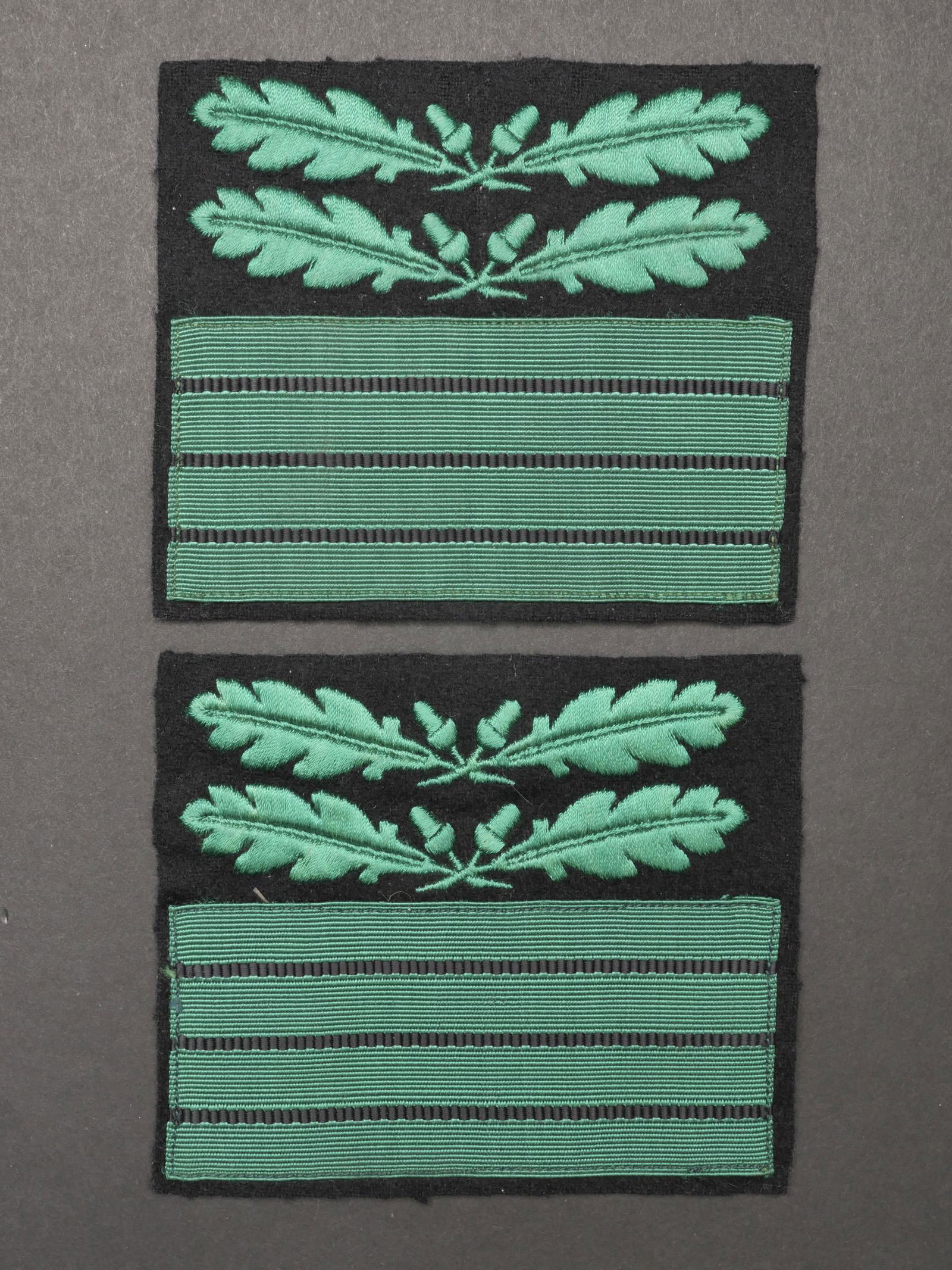 Grade de manche SS Oberfuhrer.SS Oberfuhrer rank.: Grade de manche SS Oberfuhrer. Paire homogene en drap noir, broderie verte. Jamais montes. A noter une certaine usure et patine de la piece, ainsi que quelques traces de mite. Etat II+. SS Oberfuhrer