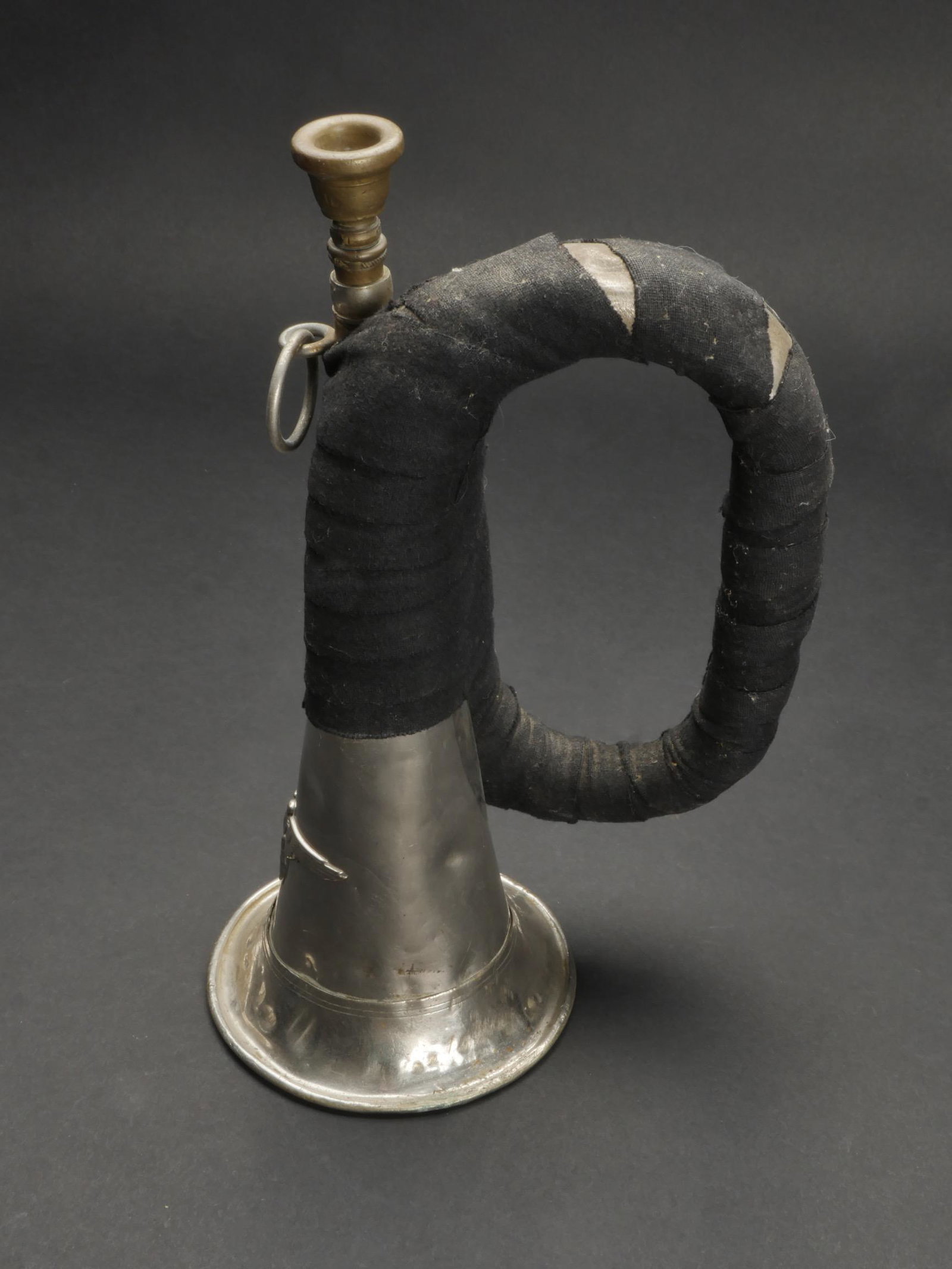 Bugle de la SS. Bugle of the SS.: Bugle de la Waffen SS. En metal couleur argent. Fortement deforme au niveau de la base. Bel aigle de la SS en relief. Ensemble de l instrument recouvert d un drap noir. Embouchure presente. Les deux a
