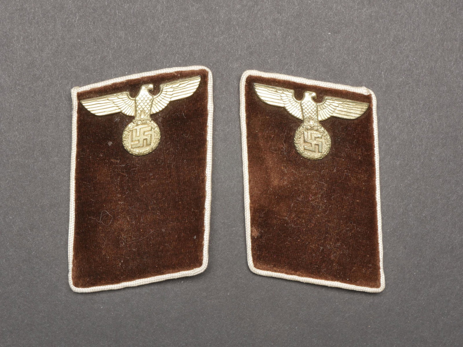 Pattes de col NSDAP. NSDAP Collar tabs.: Pattes de col NSDAP. Paire homogene en drap marron. Lisere blanc faisant le tour des pattes de col. Aigles en metal dores. Sans marquages visibles. Grade de Anworter. A noter une certaine usure et pat