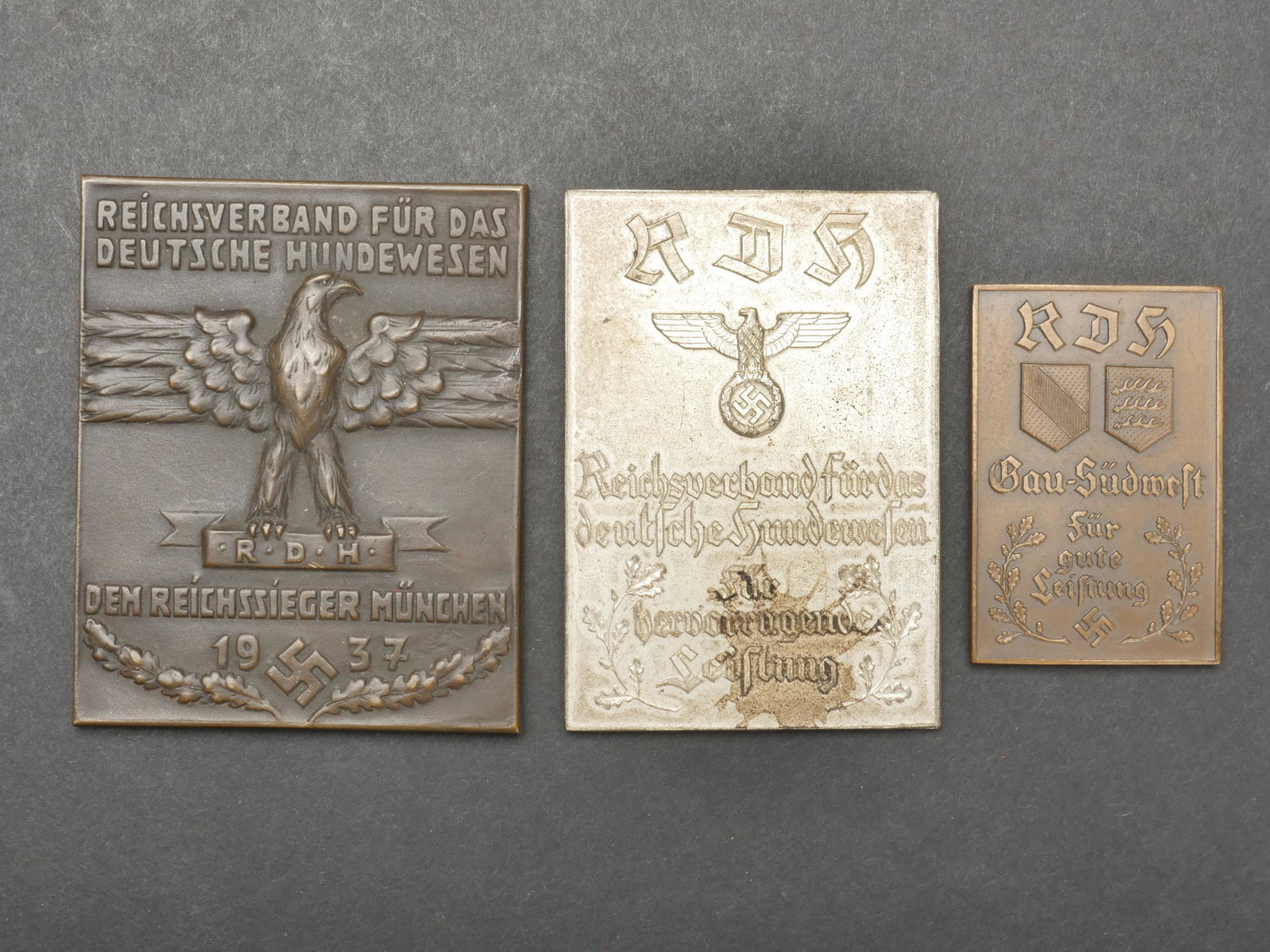 Plaquette Rechsverband. Rechsverband plate.: Plaquettes Reichsverband. Comprenant une plaquette en metal, decors en relief, bien marquee Reichsverband Fur das Deutsche Hundewesen RDH Dem Reichssieger Munchen 1937, traces de colle au dos, dimensi